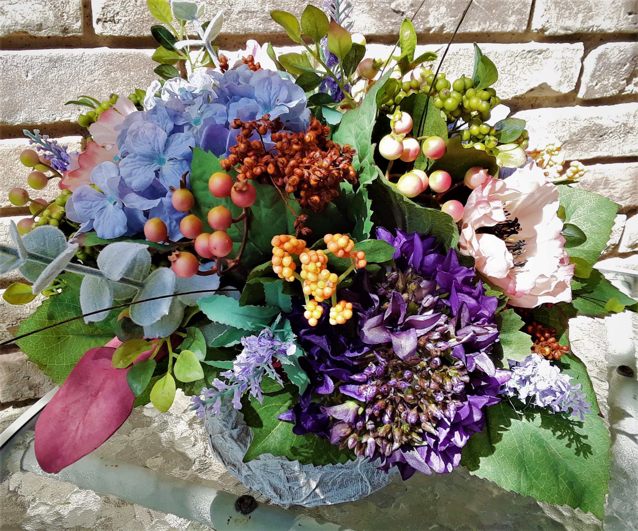 Colorful floral arrangement with blue, purple, and pink blooms in a low container