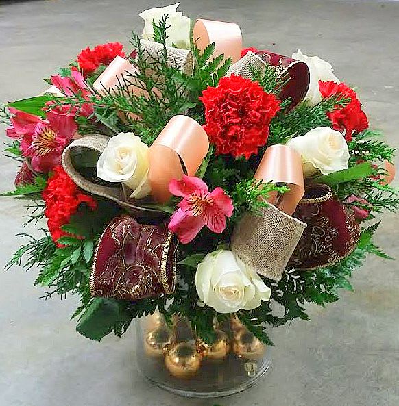 Bouquet of red carnations, white roses, and pink alstroemeria in a glass vase