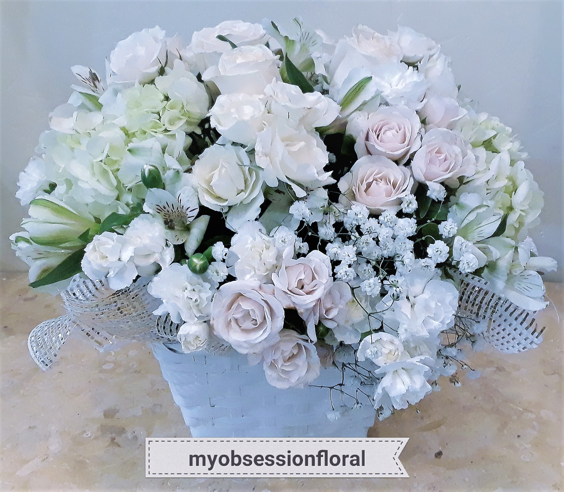 White and pale pink rose bouquet in a white basket