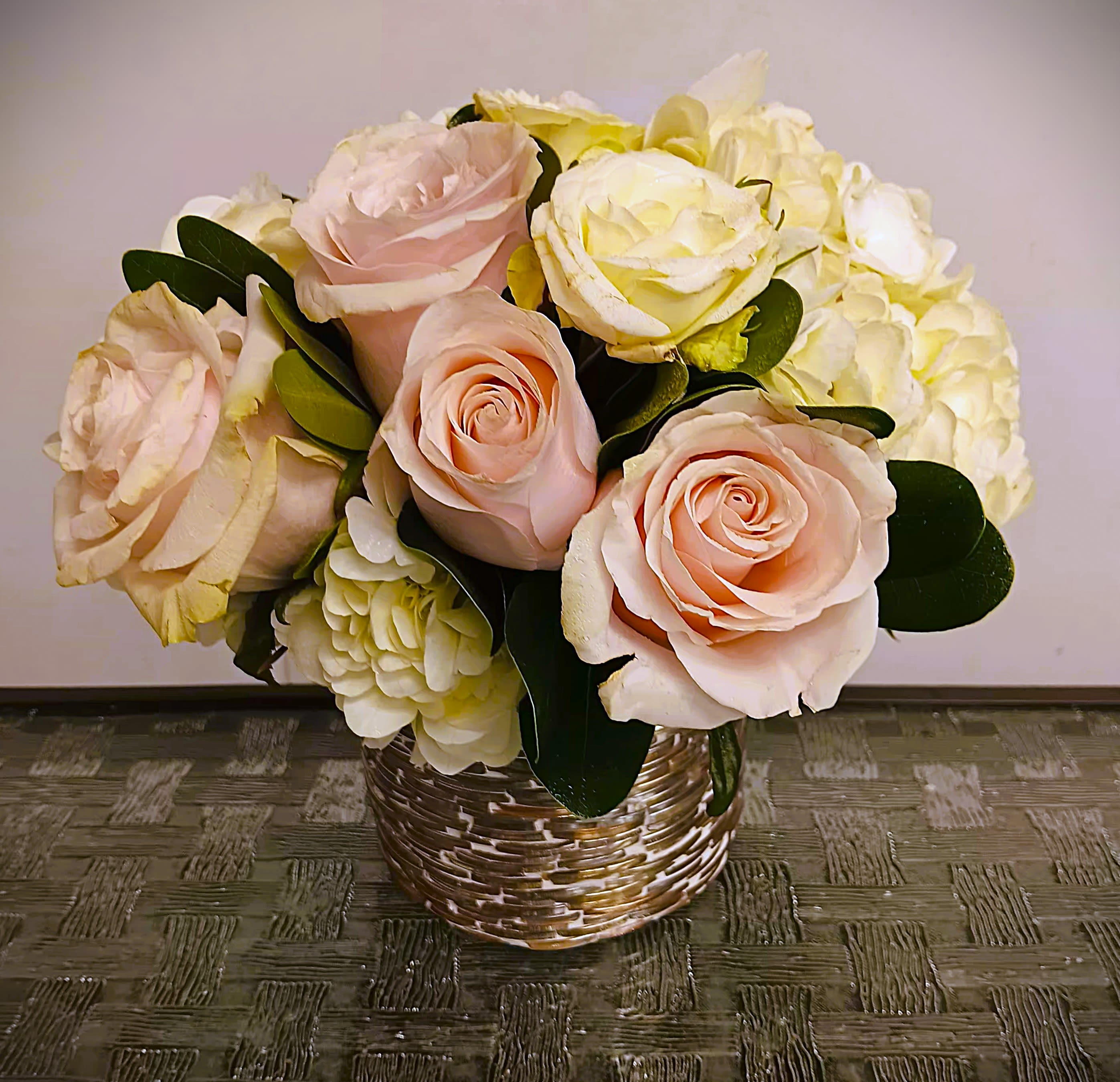 Bouquet of pale pink roses and white hydrangeas in a woven basket