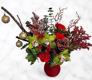Red floral arrangement in a red vase with gold ornaments and branches