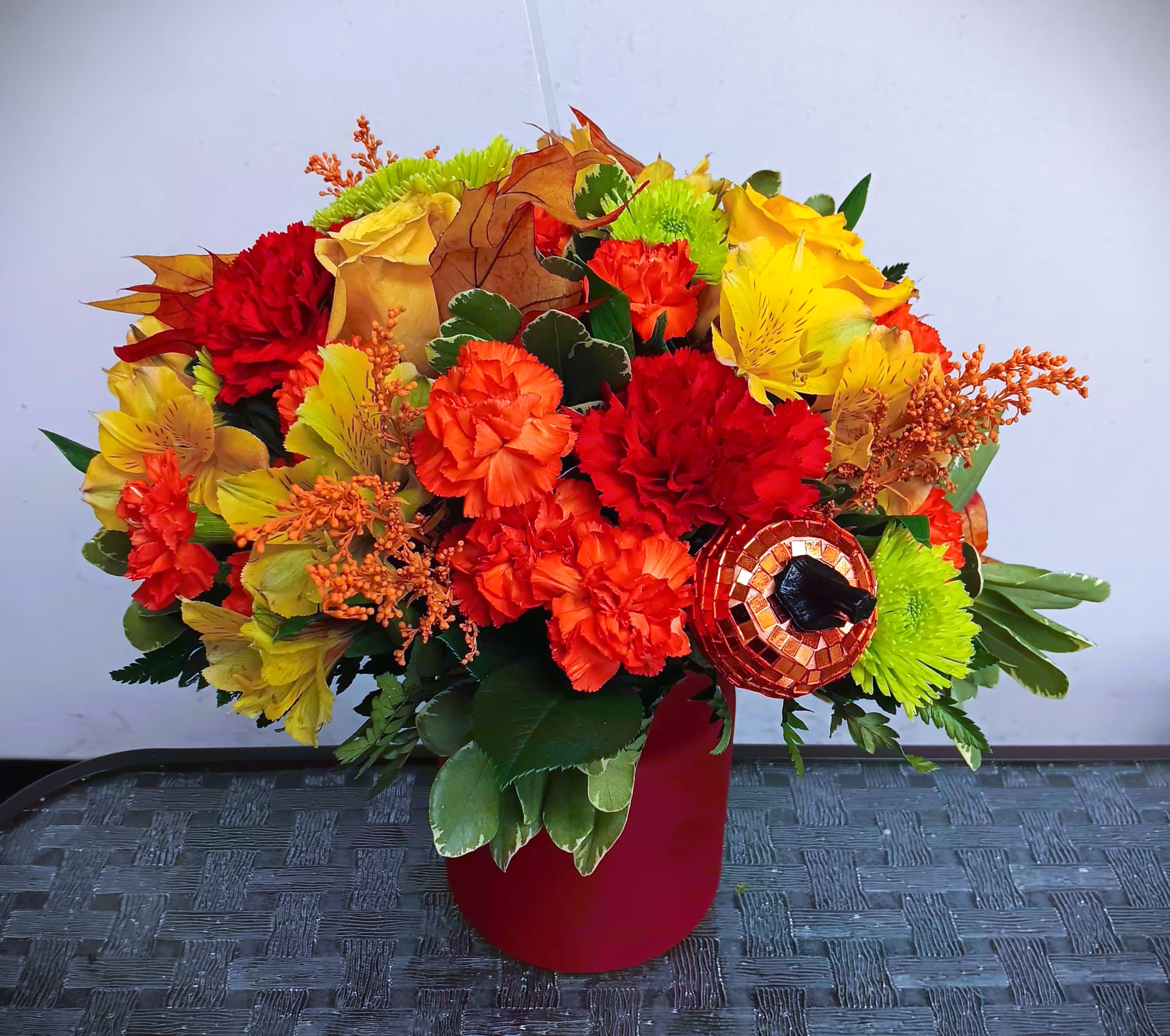 Bright autumn bouquet with red, orange, and yellow flowers in a red vase