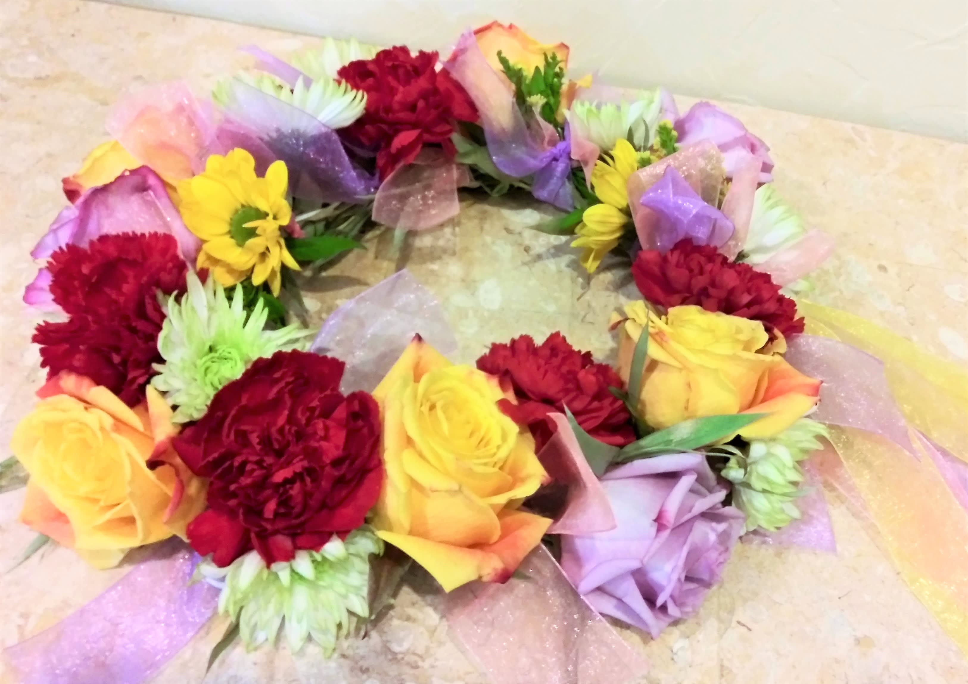 Colorful floral wreath with roses and carnations on a light surface