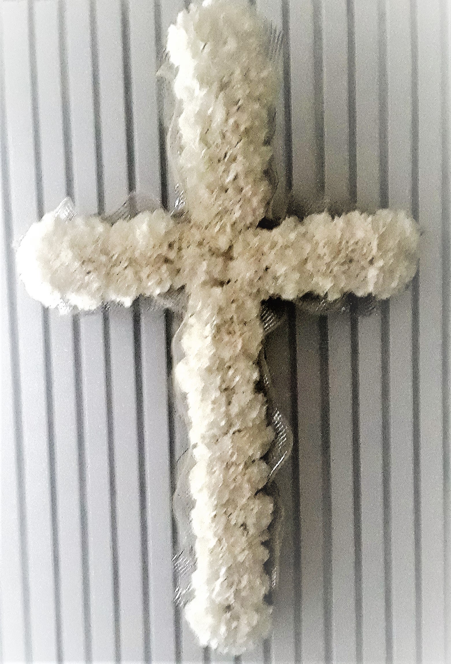 White floral cross on a ribbed gray background