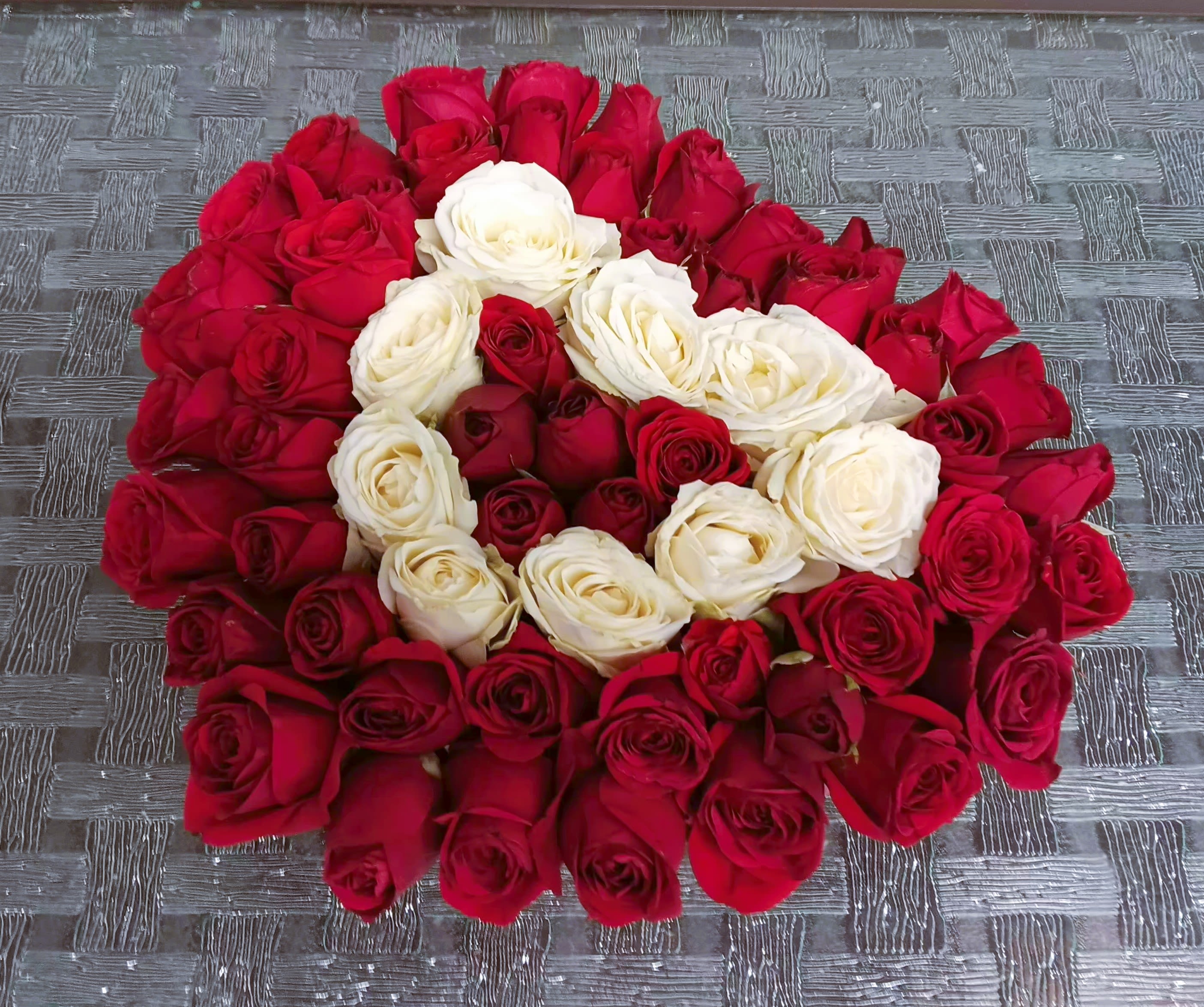 A large arrangement of red and white roses laid in a circular pattern.