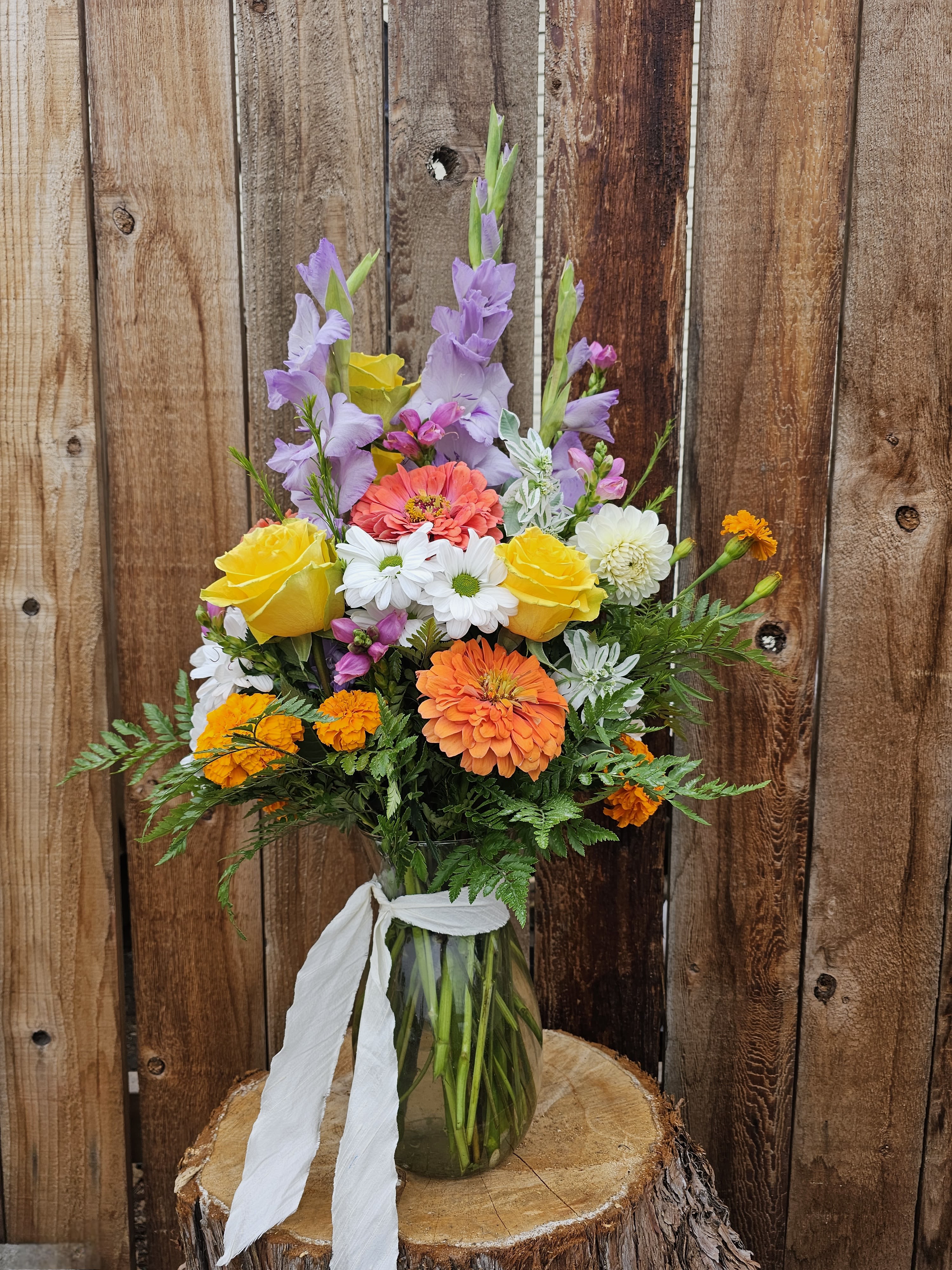 Colorful mixed bouquet in a glass vase with a white ribbon