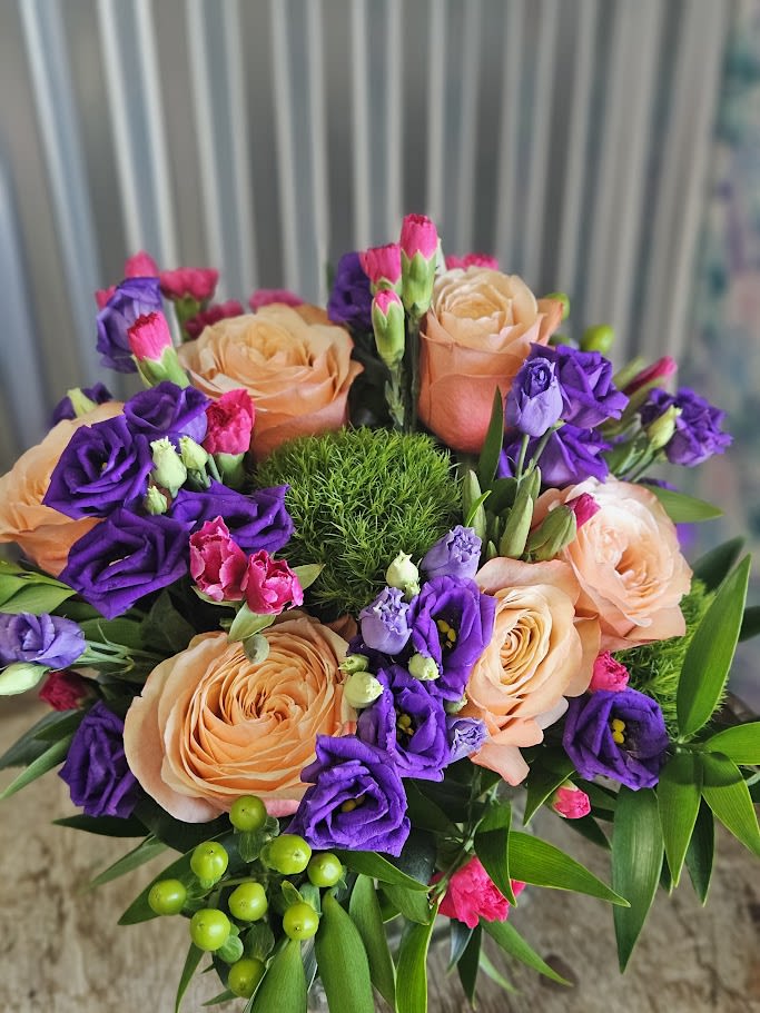 Peach roses and purple lisianthus in a round bouquet