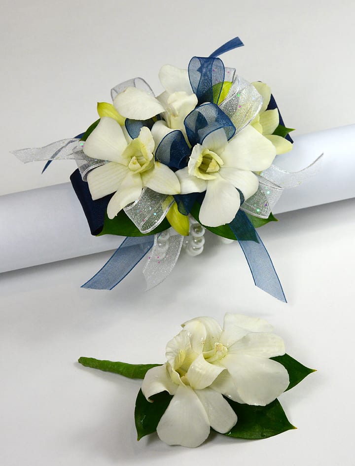 White floral wrist corsage with navy and silver ribbons and matching boutonniere.