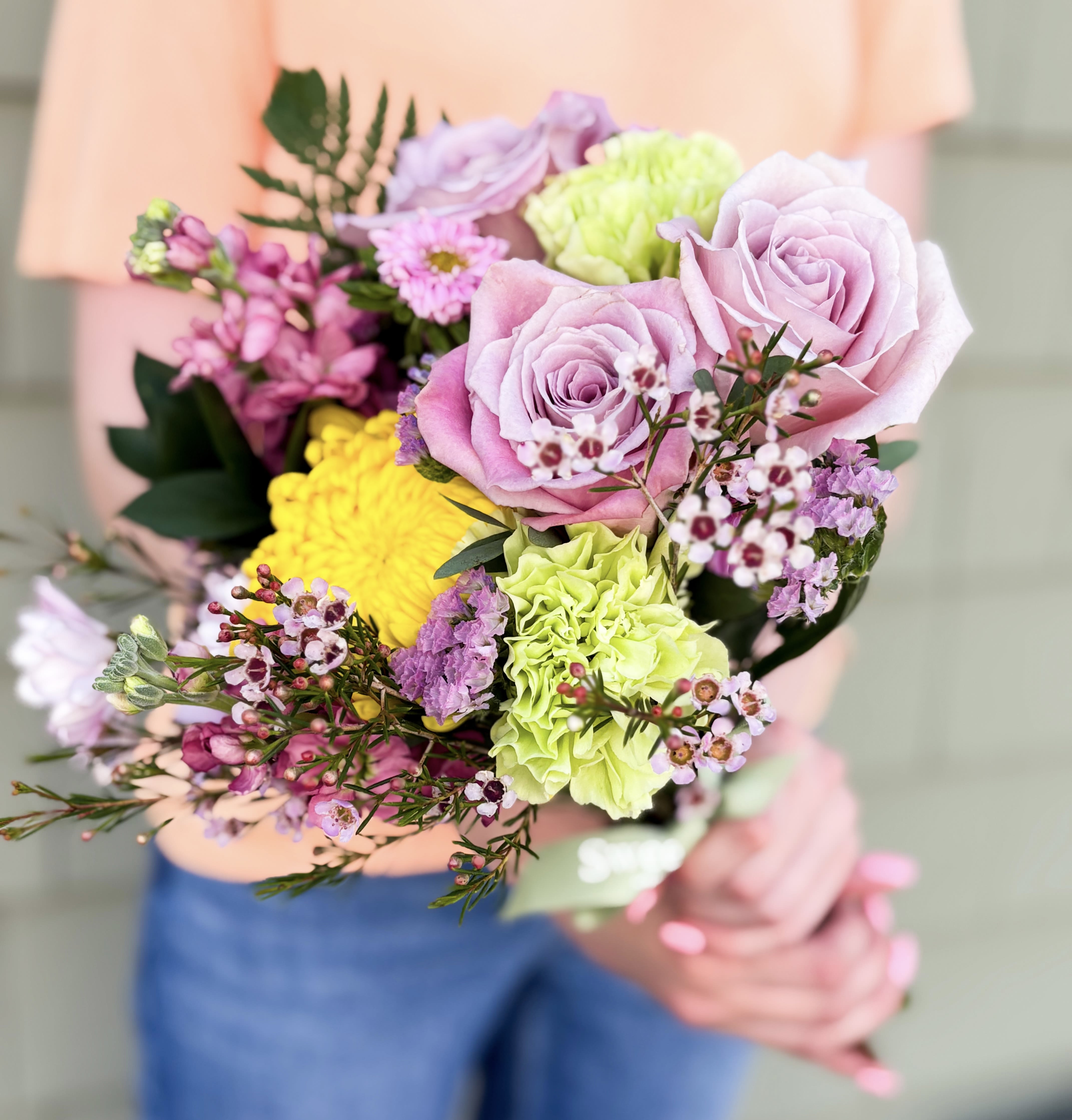 Handheld bouquet of pink and green flowers with yellow accents
