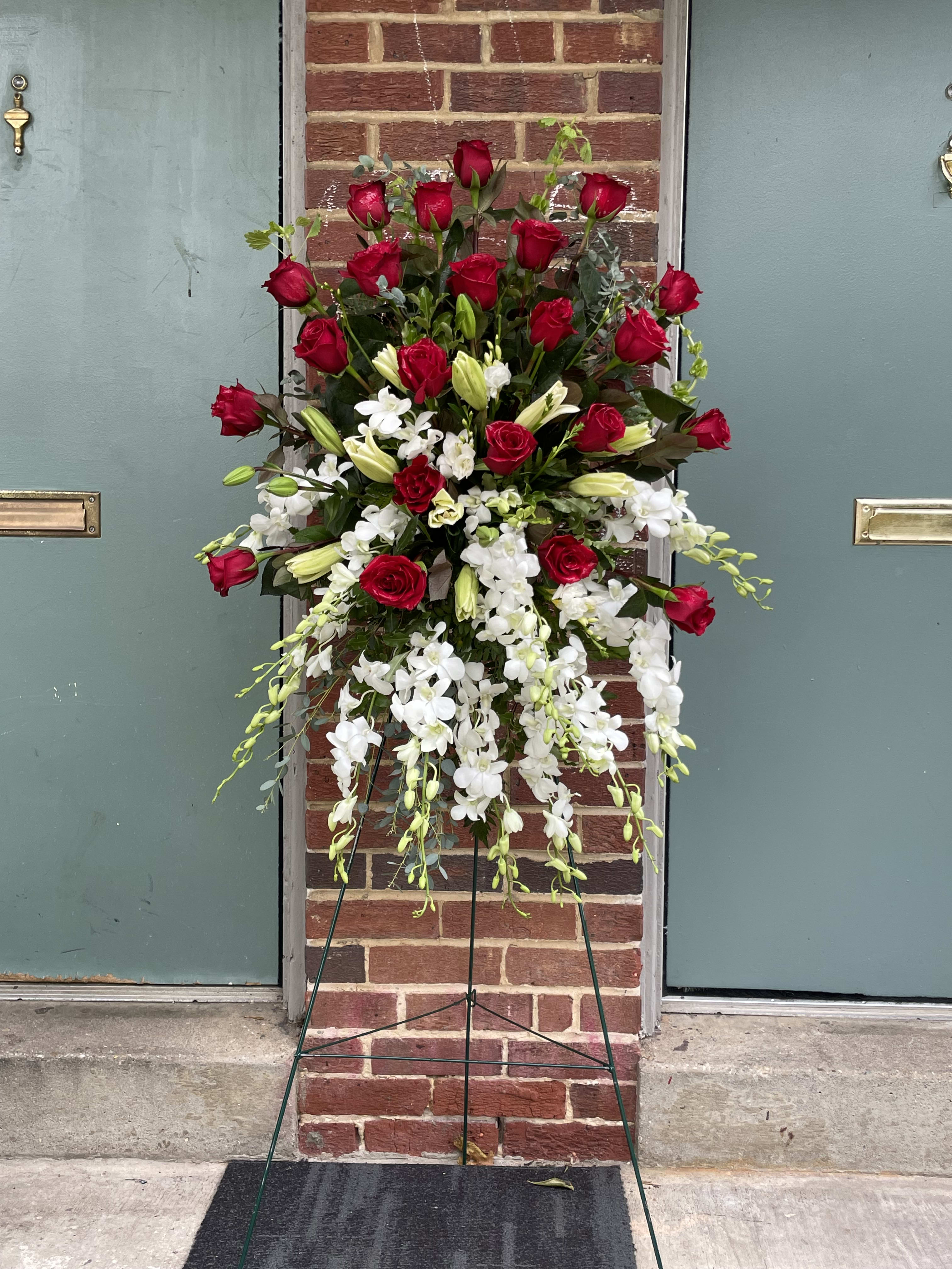 Tall standing floral spray with red roses and white orchids on a metal easel