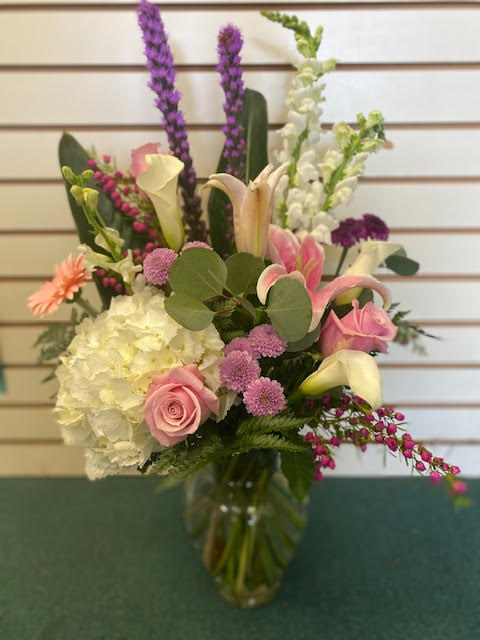 Mixed bouquet with pink roses, white hydrangea, and calla lilies in a glass vase