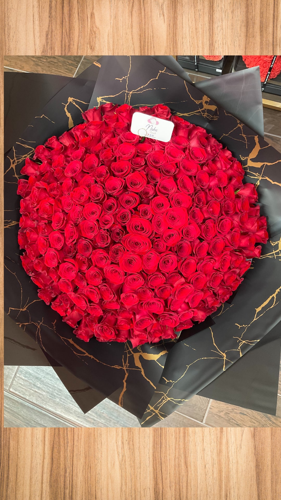 Large round bouquet of red roses wrapped in black paper