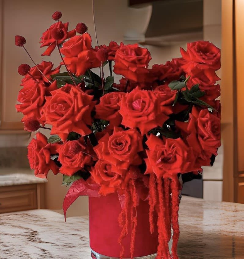 Red rose arrangement in a tall red vase with hanging red accents