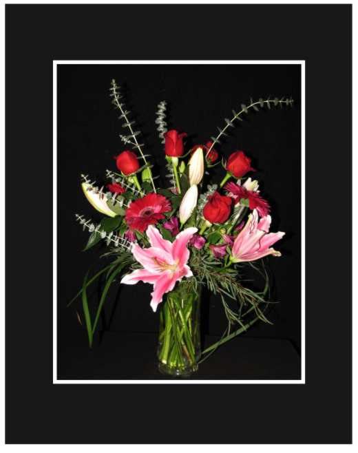 Mixed bouquet of red roses and pink lilies in a glass vase