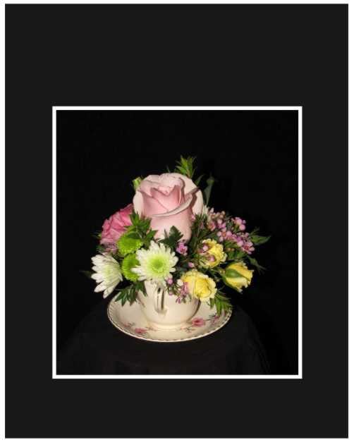 Pink rose arrangement in a teacup with small mixed flowers