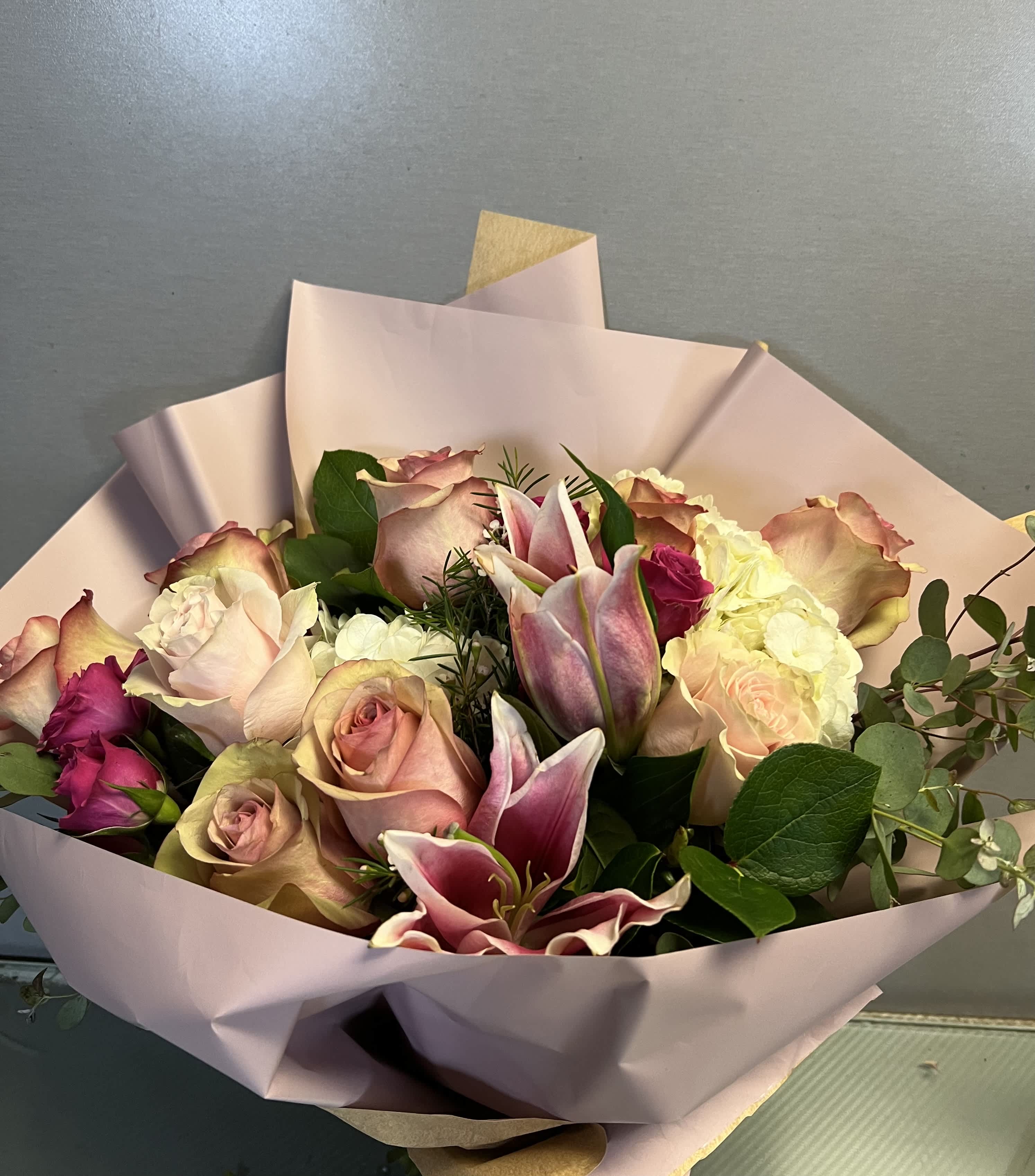 Bouquet of pink roses and lilies wrapped in pale pink paper