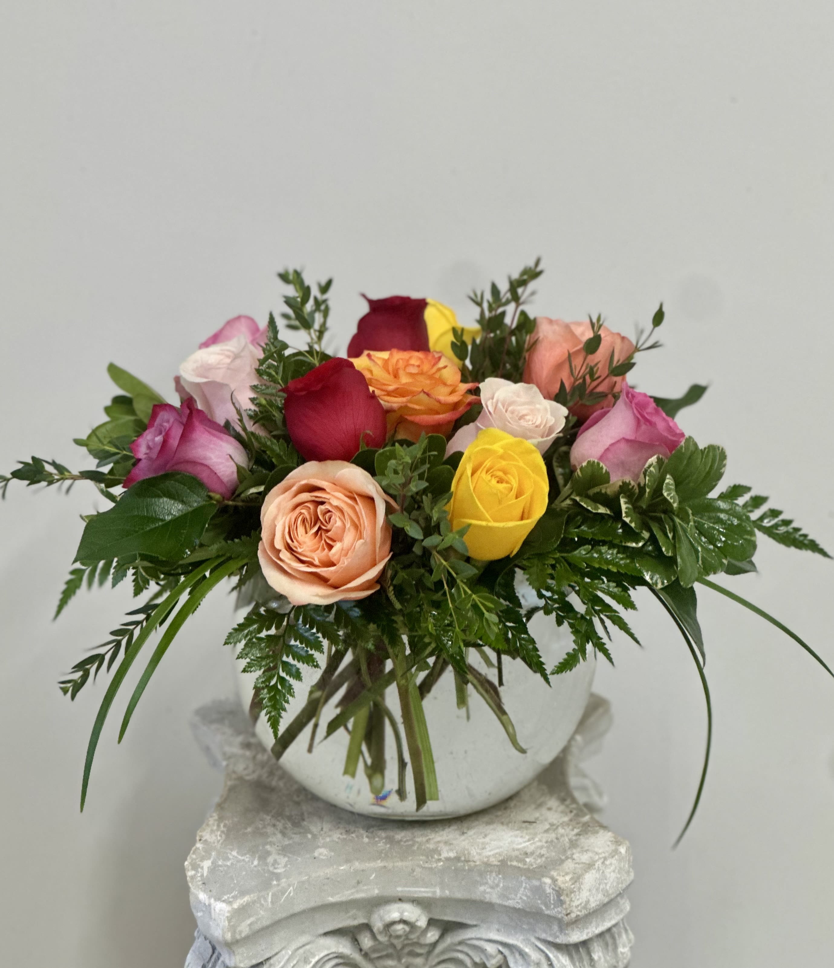 Mixed roses arranged in a round white vase