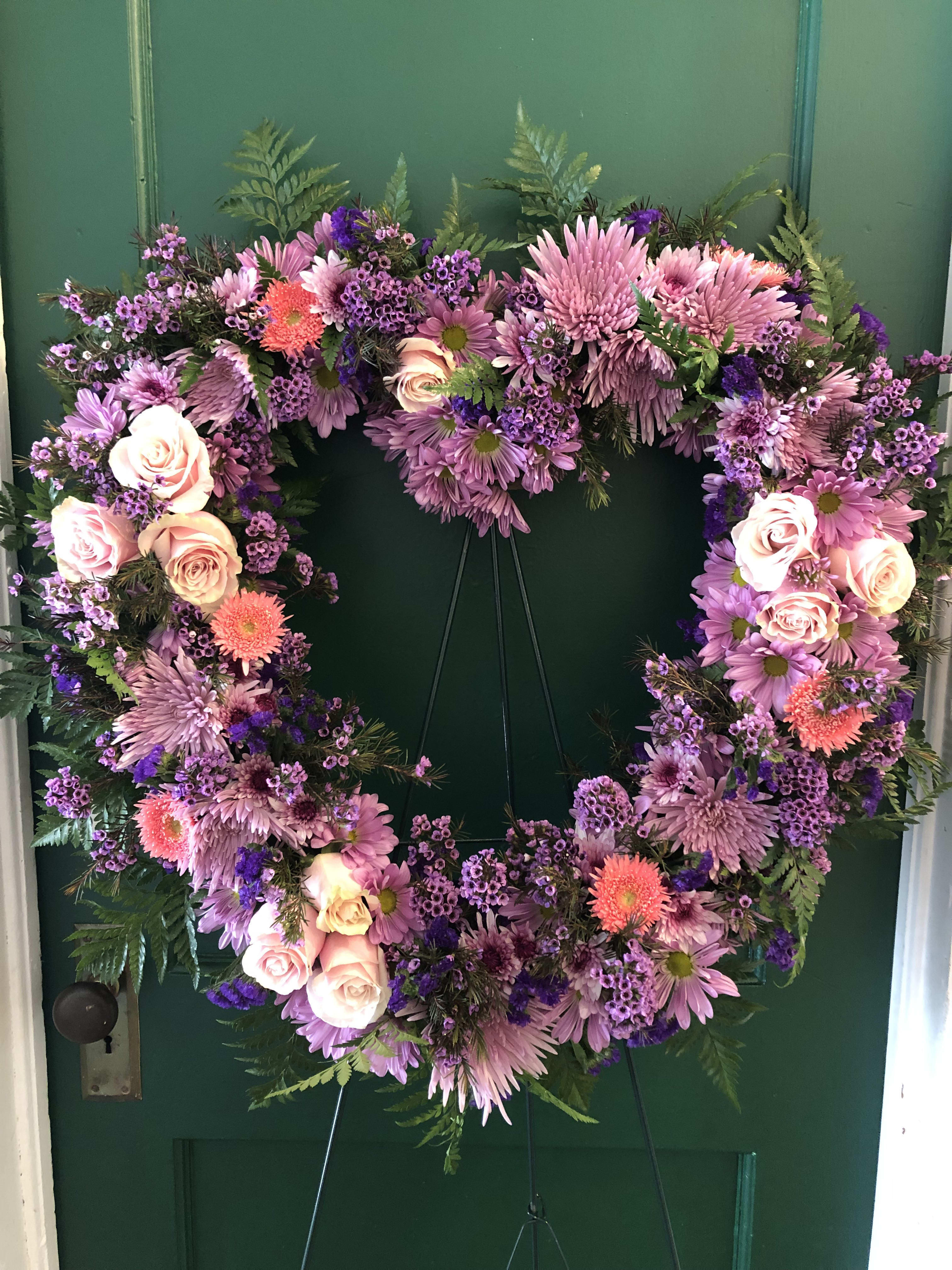 Heart-shaped floral wreath with pink and purple flowers on a green door