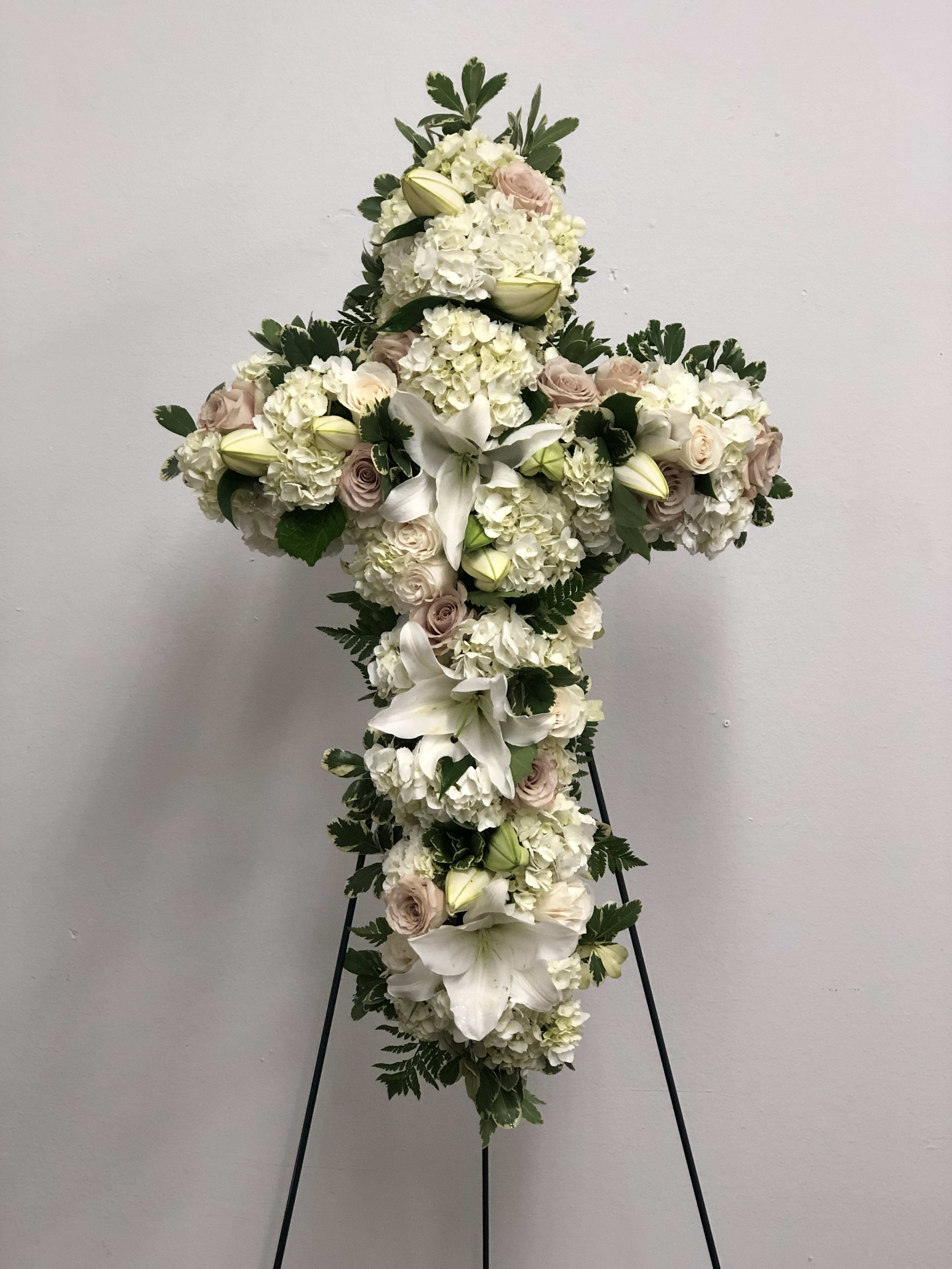 Cross-shaped floral spray with white lilies, hydrangeas, and pale roses