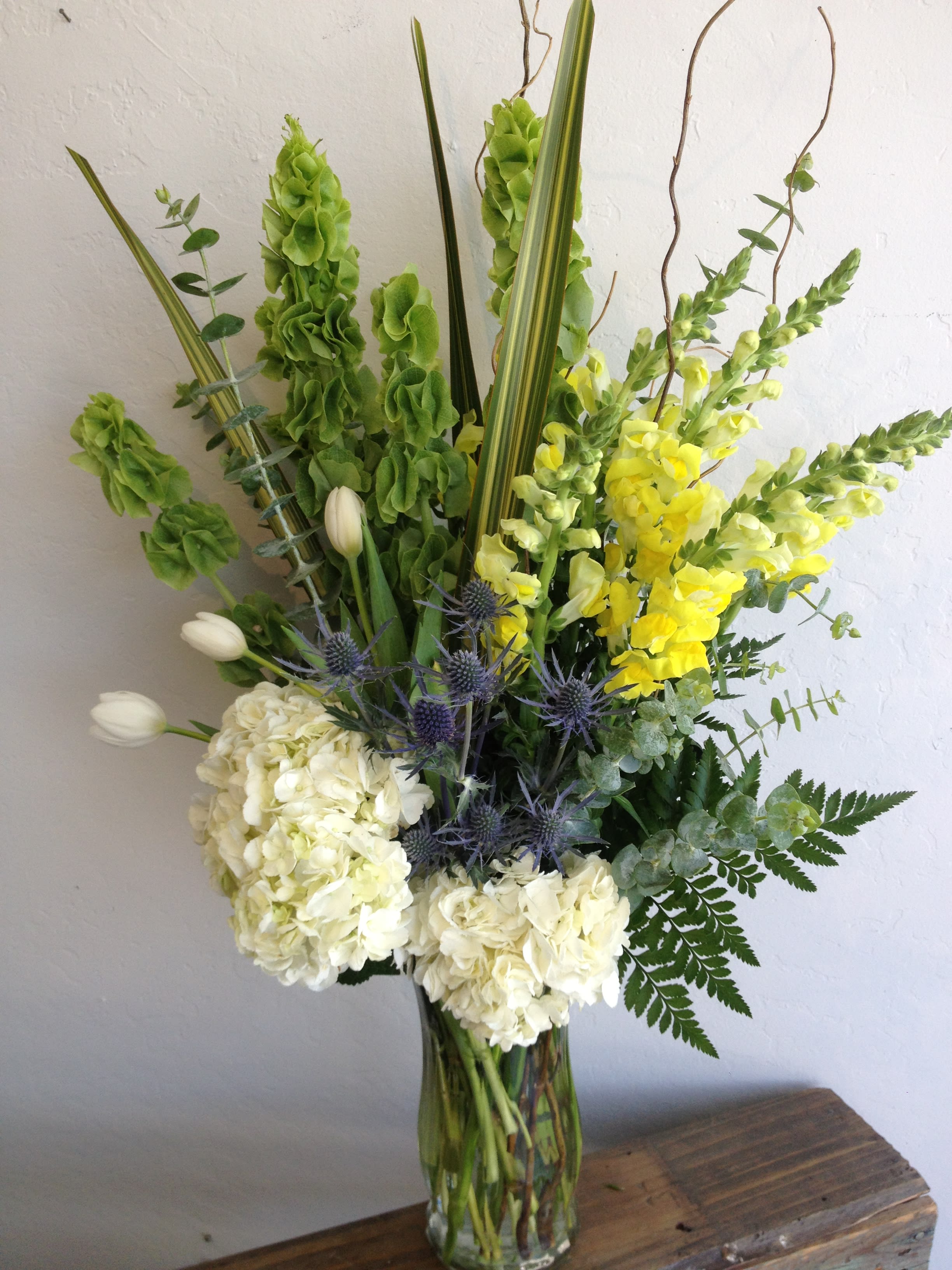 Braveheart - Tall arrangement of hydrangeas, snap dragons, seasonal greens, bells of Ireland, tulips and blue thistle.  This design is a perfect mix of masculine, rustic and modern.