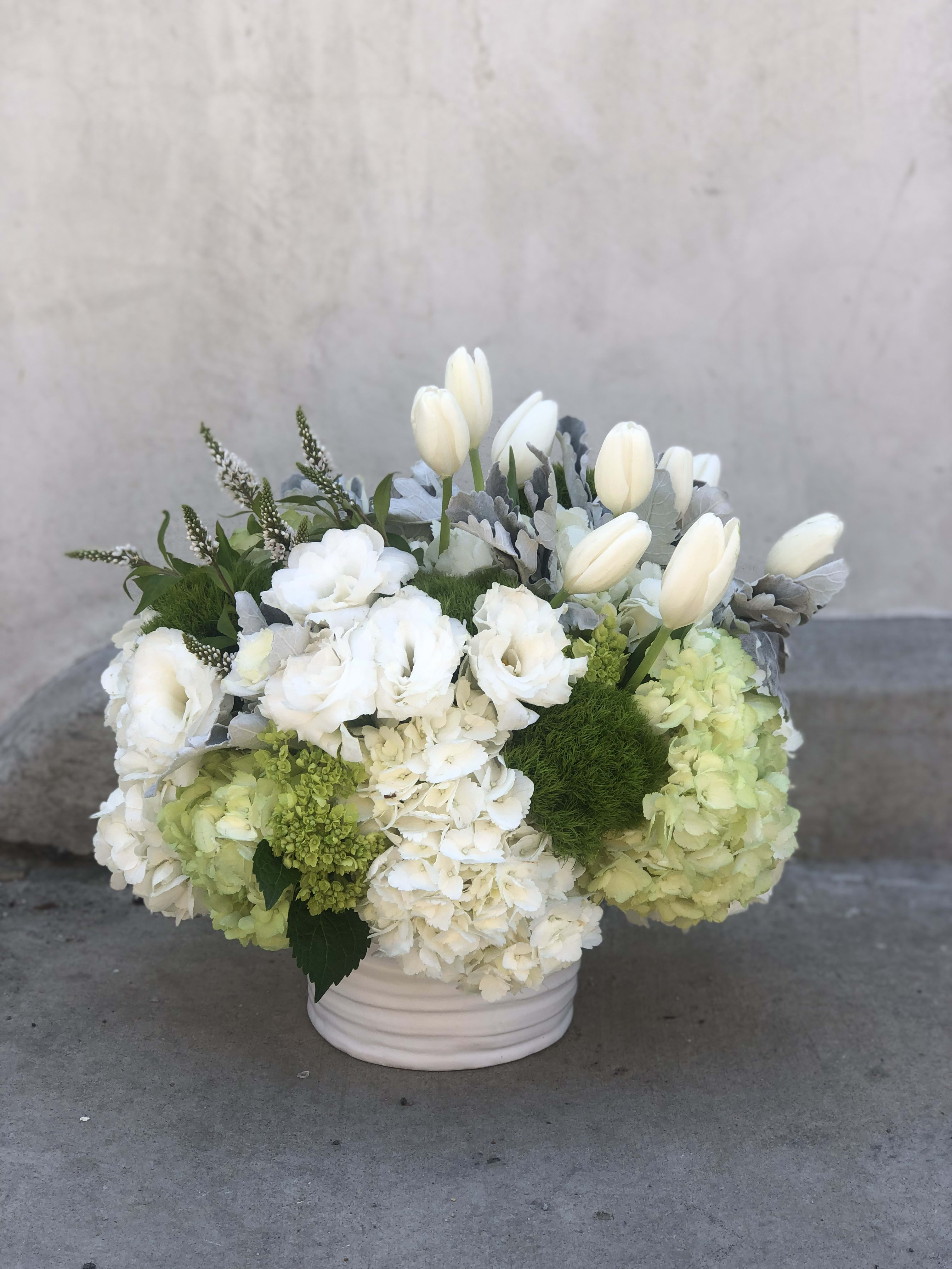 Moet et Chandon (in her pretty cabinet) - Let them eat cake she say's just like Marie Antionette!  Inspired by the song Killer Queen, this exquisite lush bunch is classy and full of hydrangeas, lisianthks, dianthus, veronica, dusty miller, and tulips.  This beauty sings "High End" + "Expensive Taste"  *Arr. measures approx. 9 in round, 9in tall