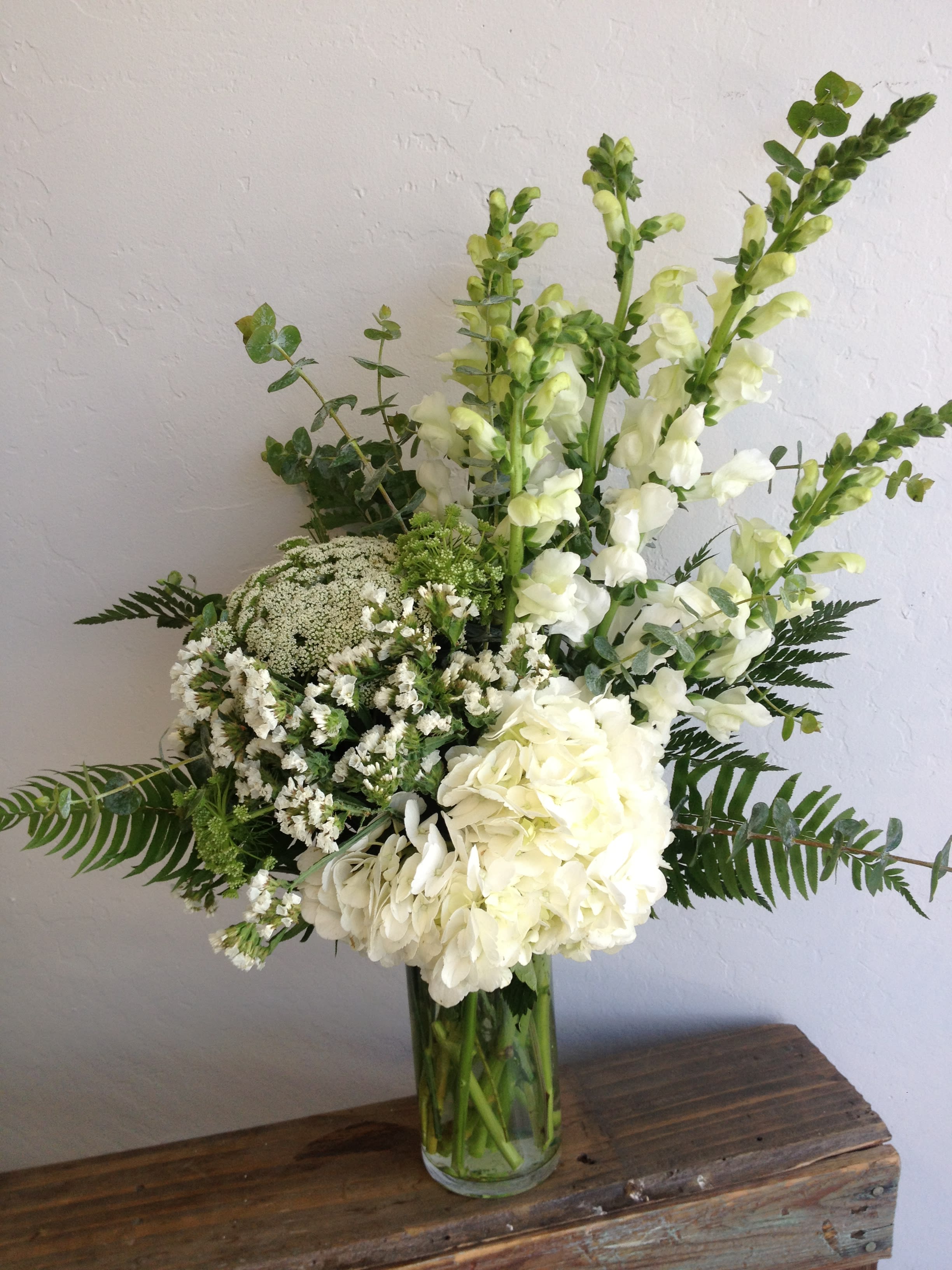 White flowers and greenery arranged in a clear glass vase