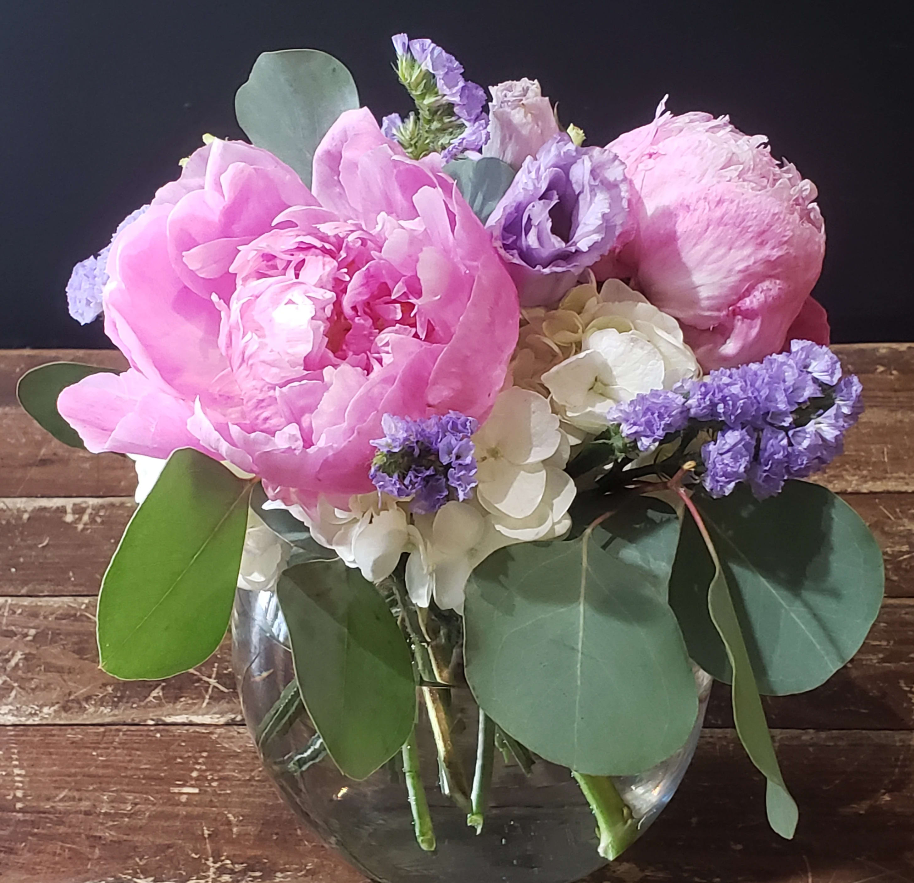 Pink and lavender flowers arranged in a clear glass vase