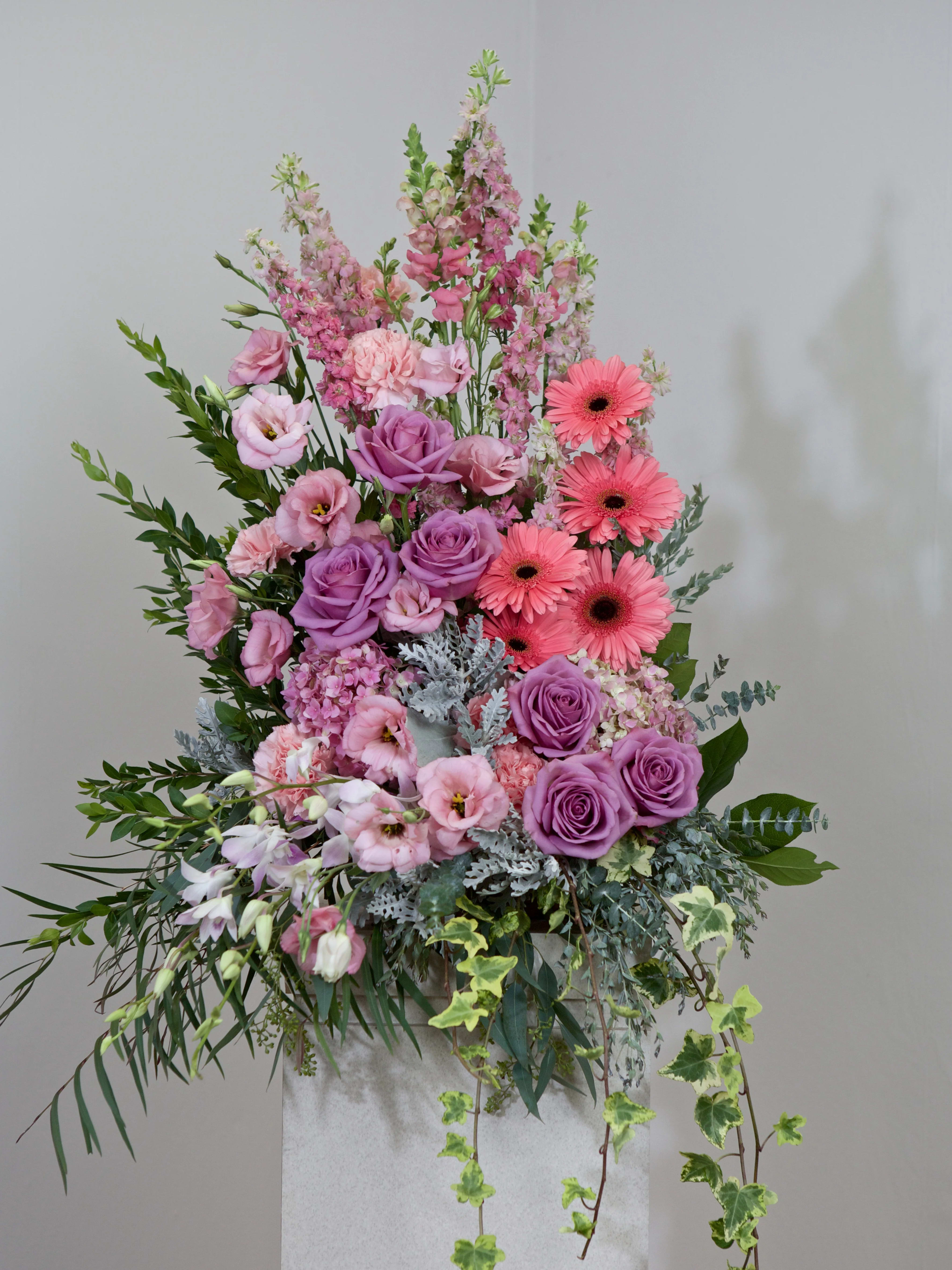 Tall pink and purple floral arrangement with roses and gerbera daisies