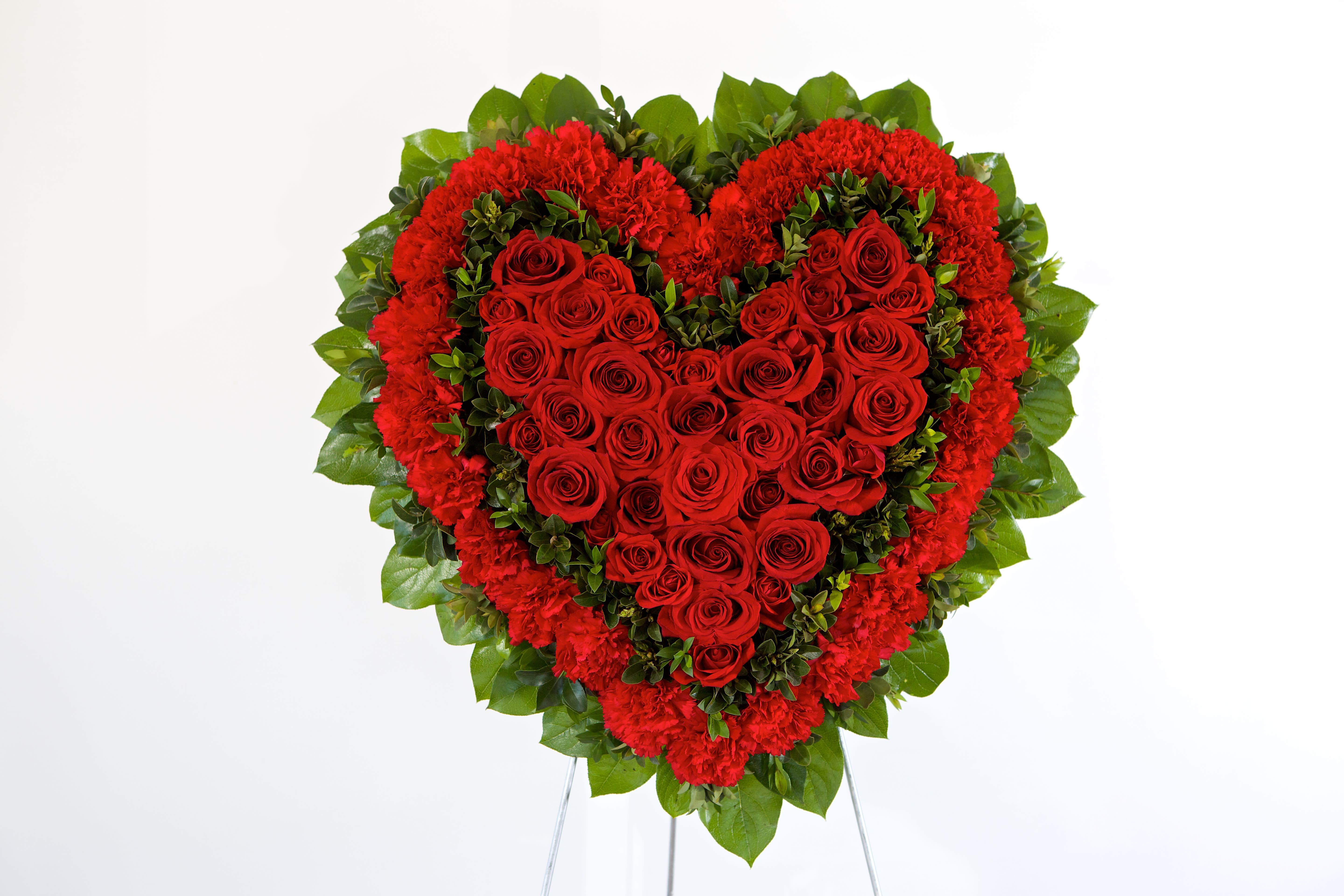 Heart-shaped red rose and carnation arrangement on a stand