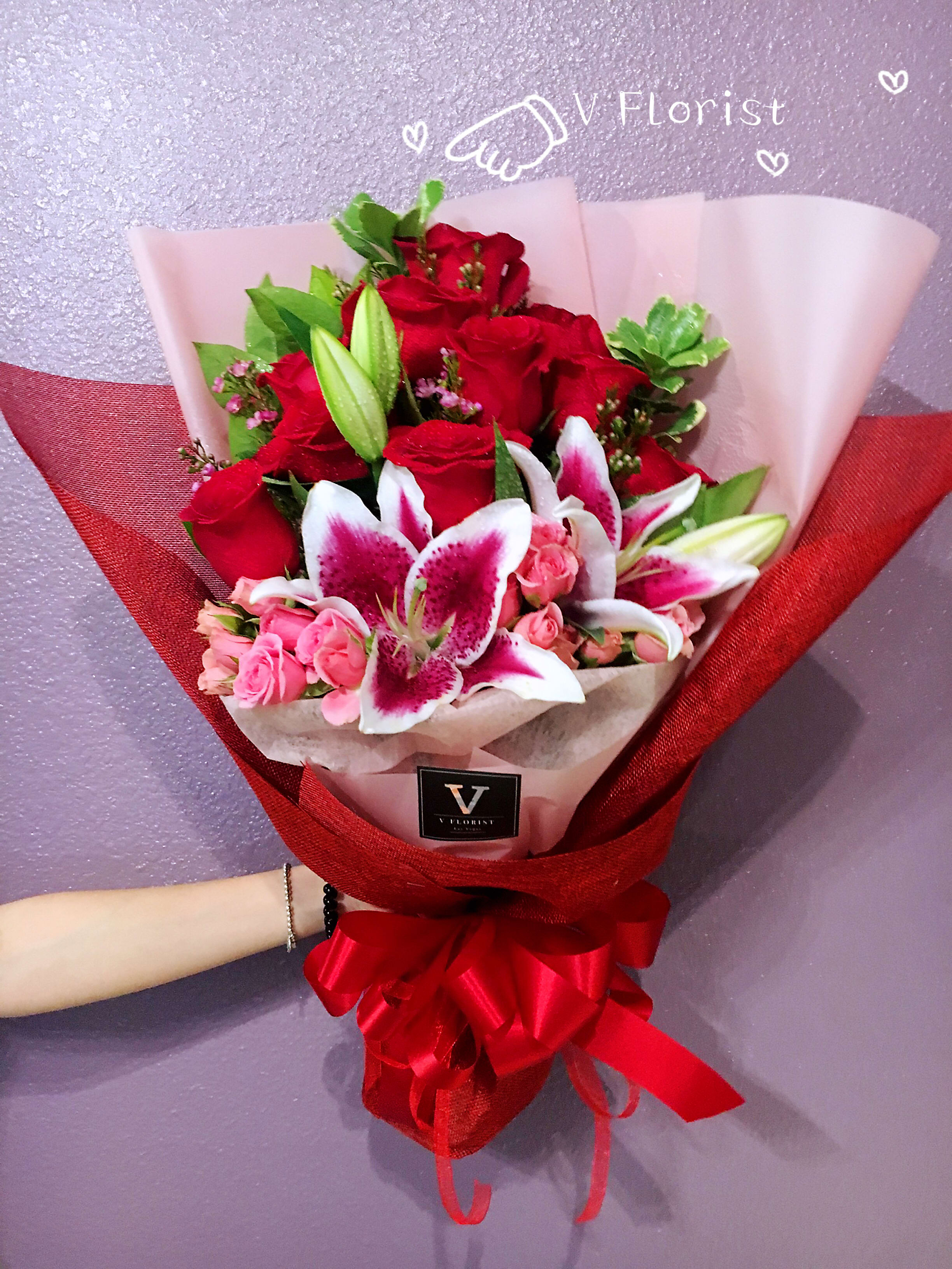 Bouquet of red roses and pink lilies wrapped in red and white paper