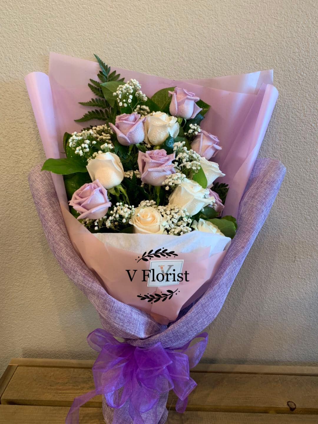 Bouquet of pale pink and white roses wrapped in pink paper