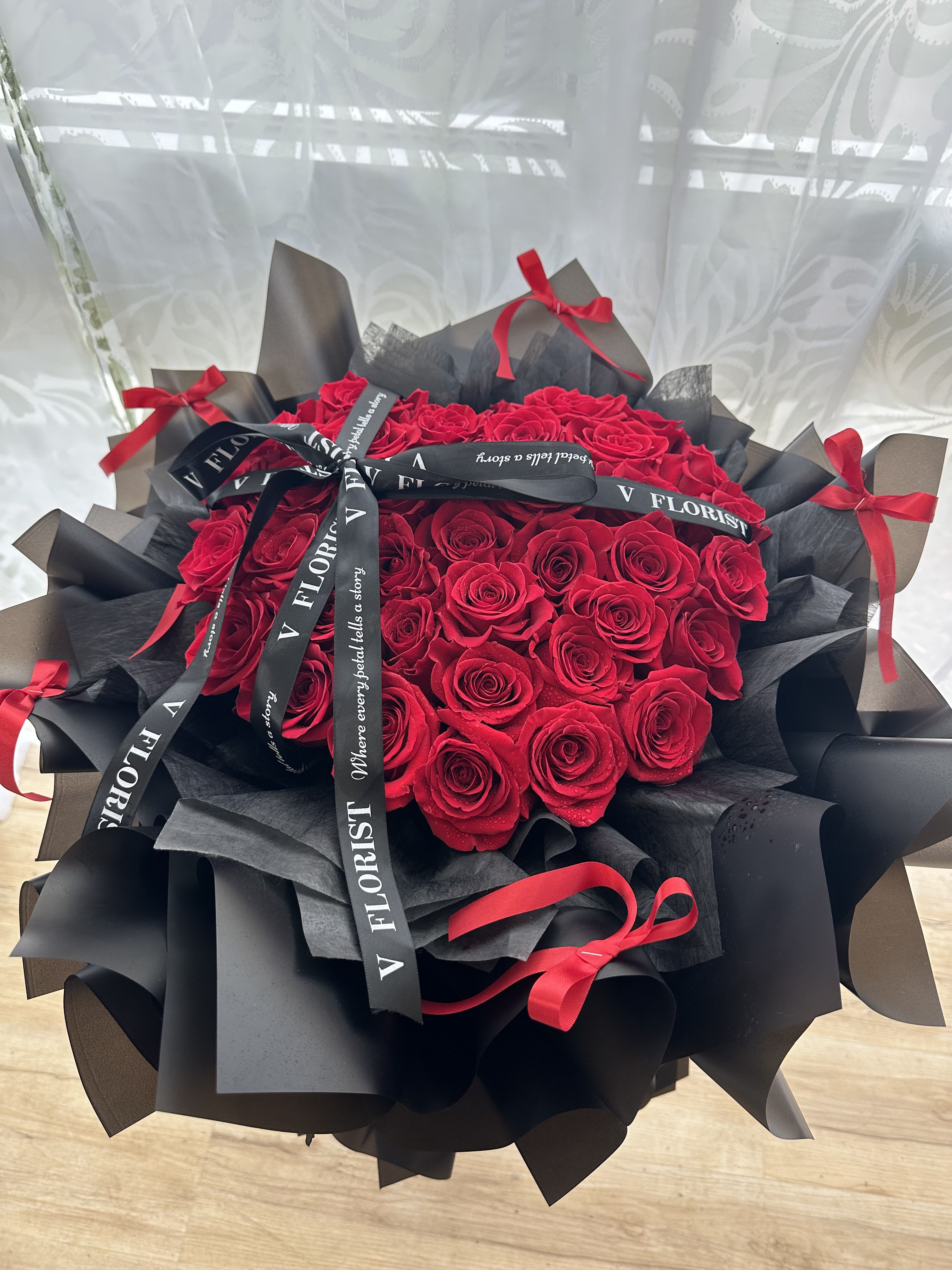 Bouquet of red roses wrapped in black paper with red ribbons