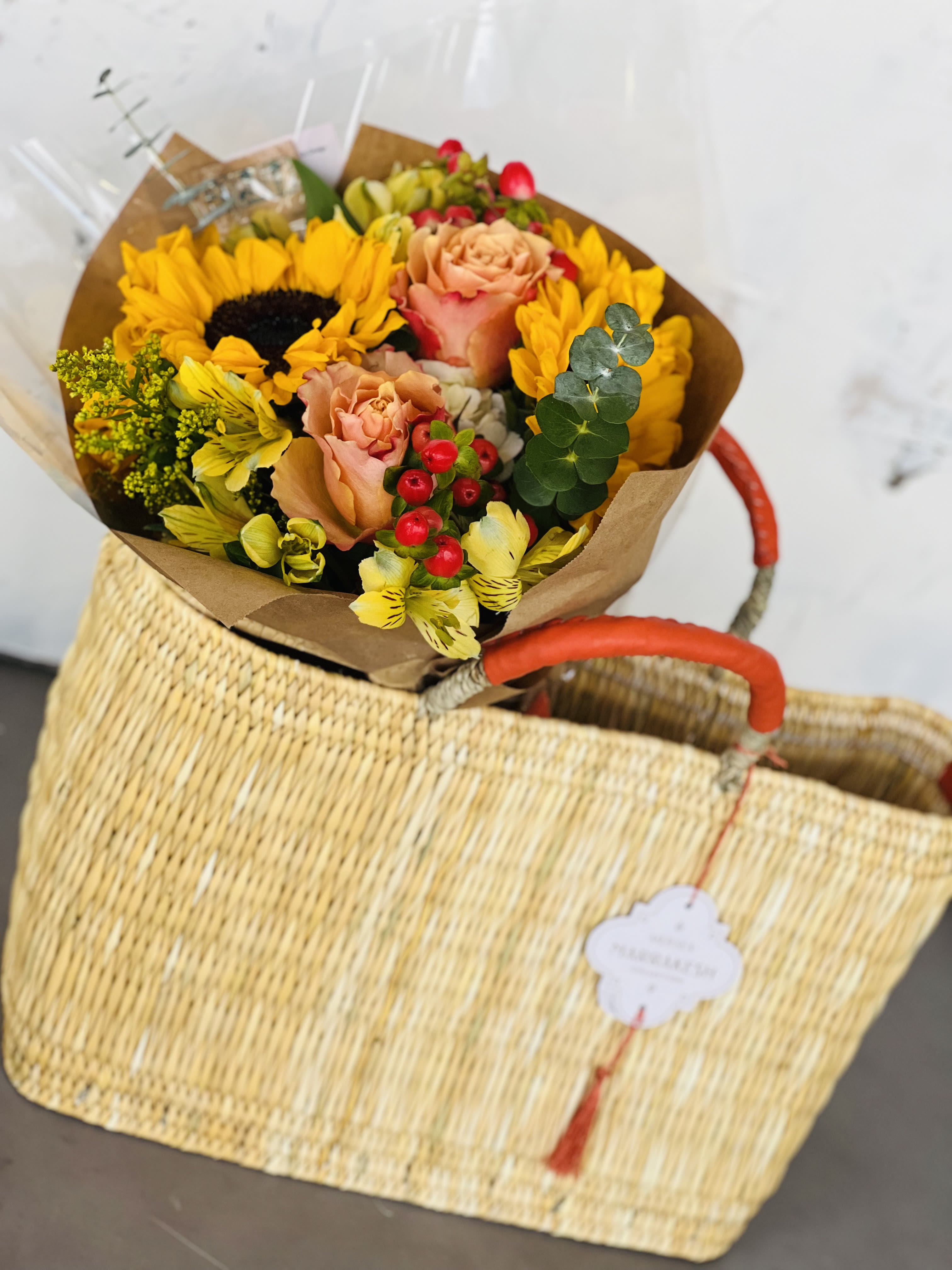 Bouquet of sunflowers, peach roses, and yellow flowers in brown paper