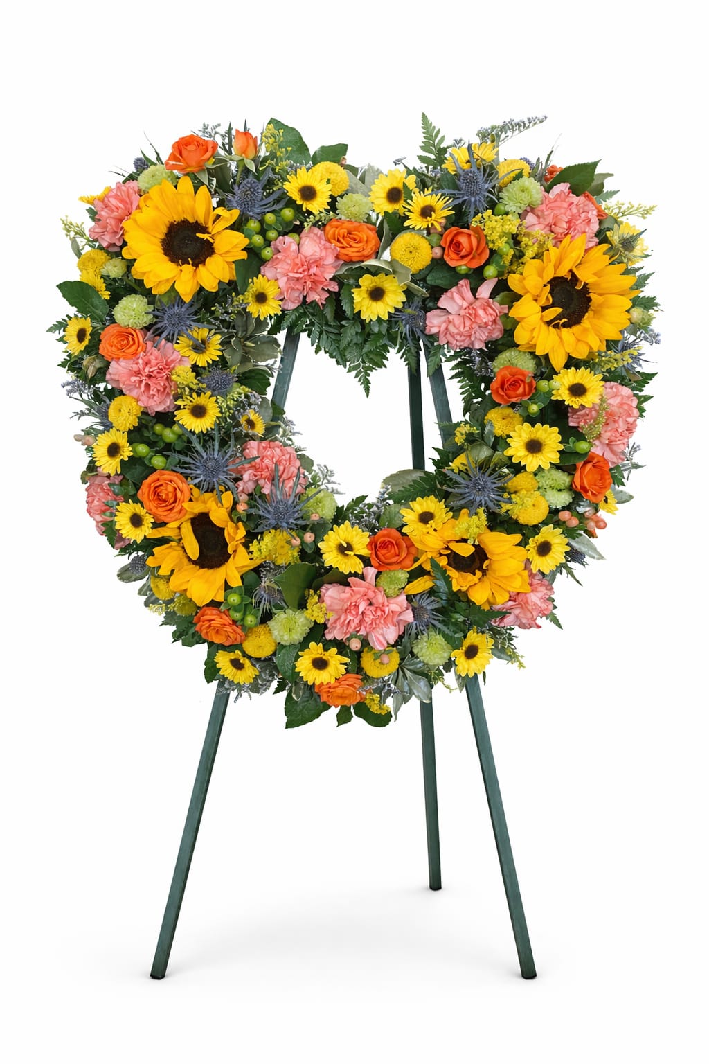 Sunlit Heart Tribute - A vibrant and heartfelt tribute designed in a beautiful heart shape, symbolizing everlasting love. This arrangement features radiant sunflowers paired with warm orange roses, soft coral carnations, and cheerful yellow daisies, all accented with textured blooms and lush greenery.  Full of warmth and light, this piece brings a sense of comfort and remembrance, making it a meaningful way to honor a loved one. Displayed on an easel, it creates a stunning and uplifting presence at any service.