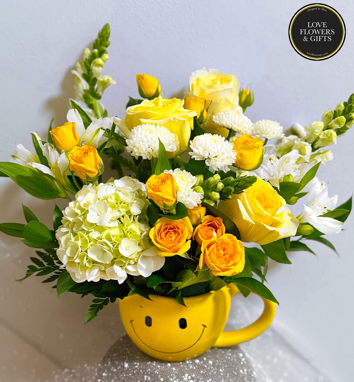 Cheerful yellow and white flower arrangement in a yellow smiley-face mug