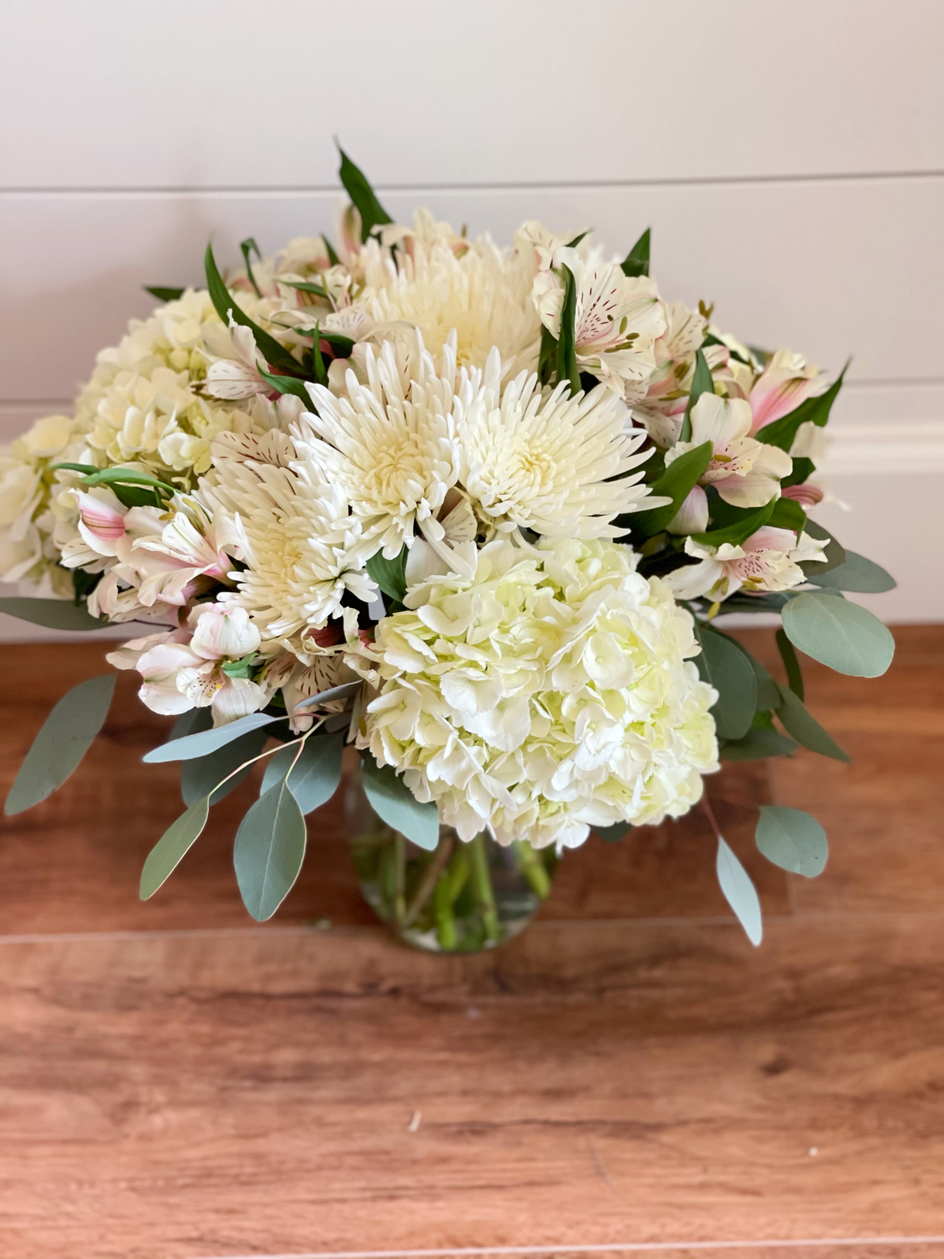 White bouquet with hydrangea, chrysanthemums, and pale pink alstroemeria in a glass vase
