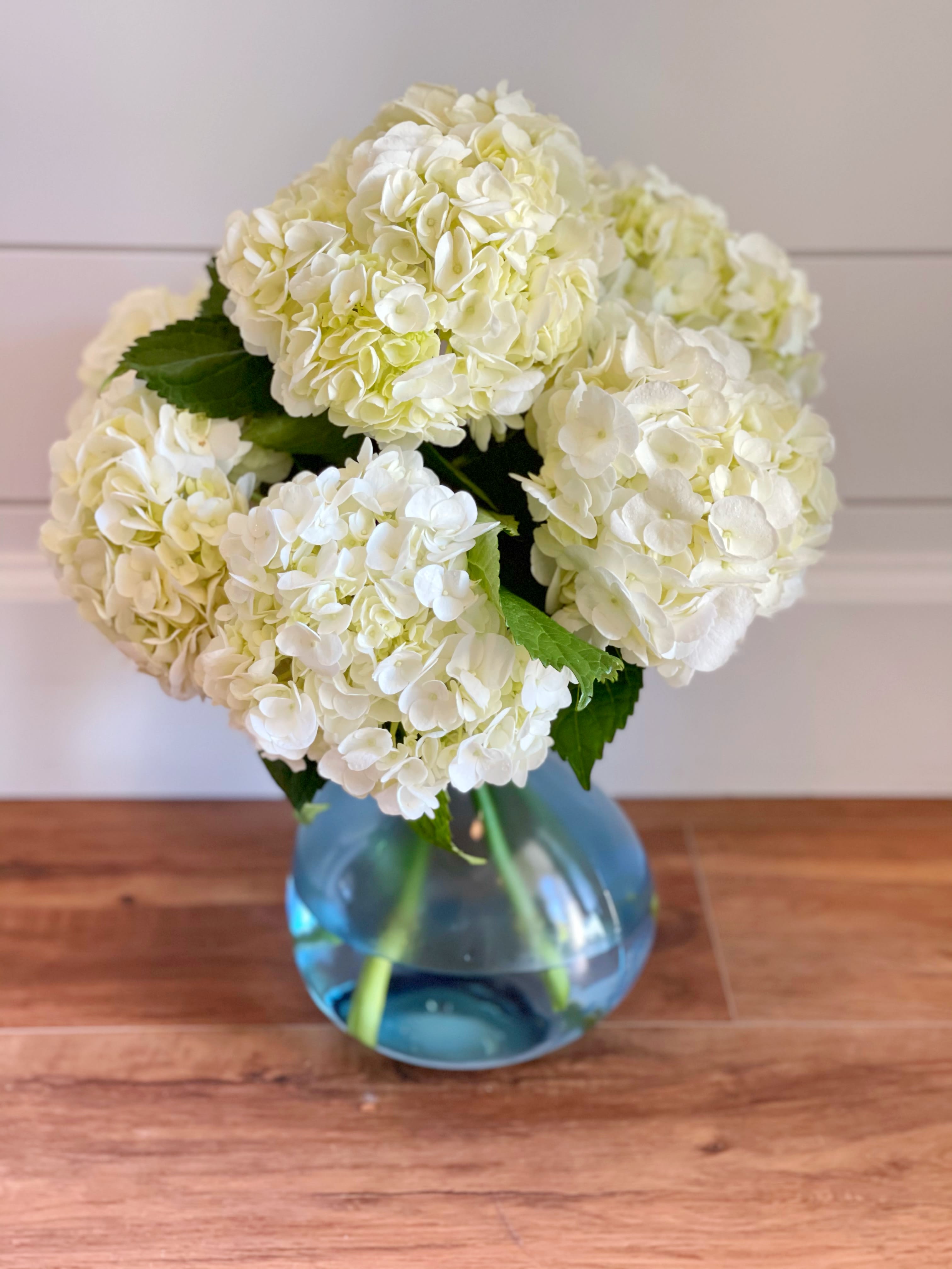White hydrangea bouquet in a blue glass vase