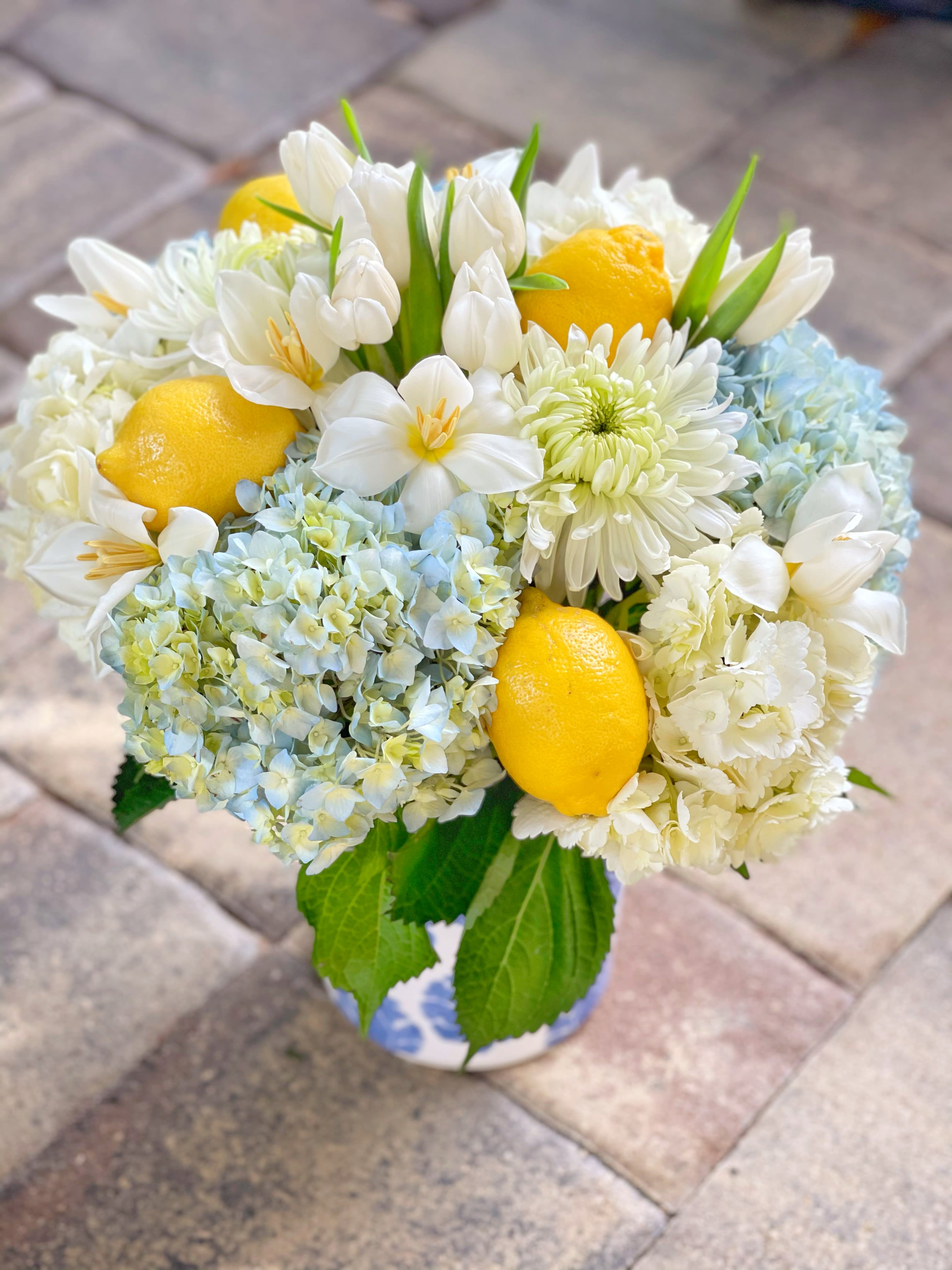 Bouquet of white flowers with lemons and pale blue blooms in a vase