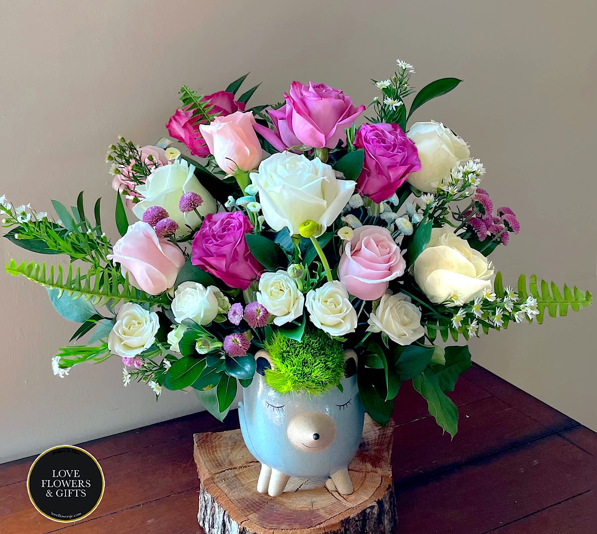 Pink and white rose arrangement in a cute animal ceramic vase with bright green moss hair.