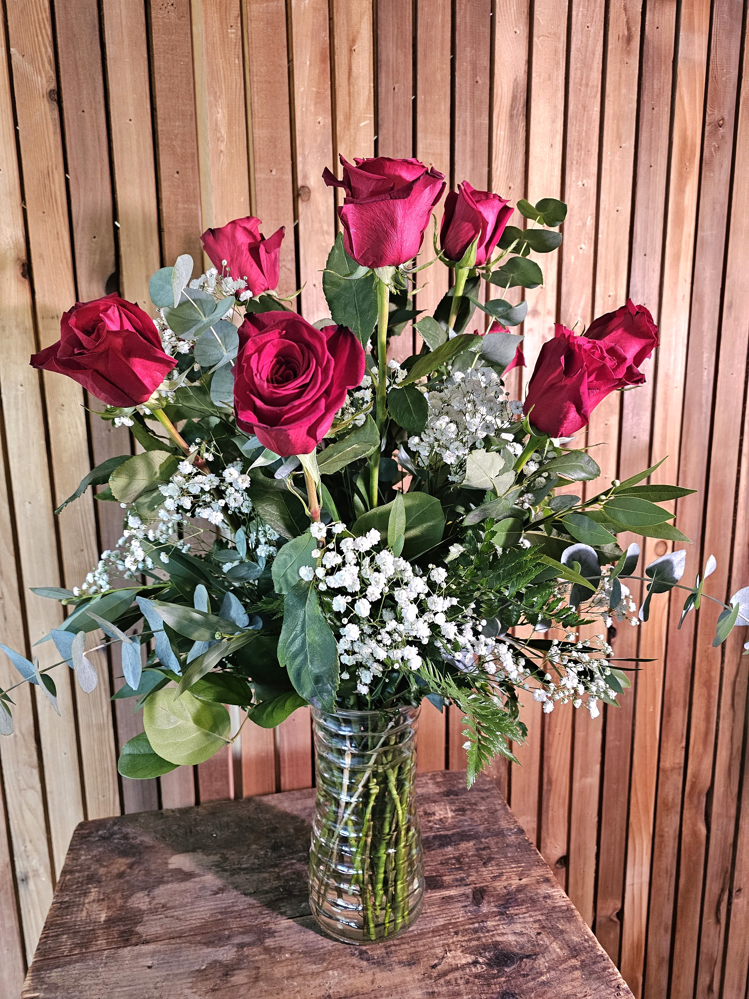 Bouquet of red roses with baby's breath in a clear glass vase