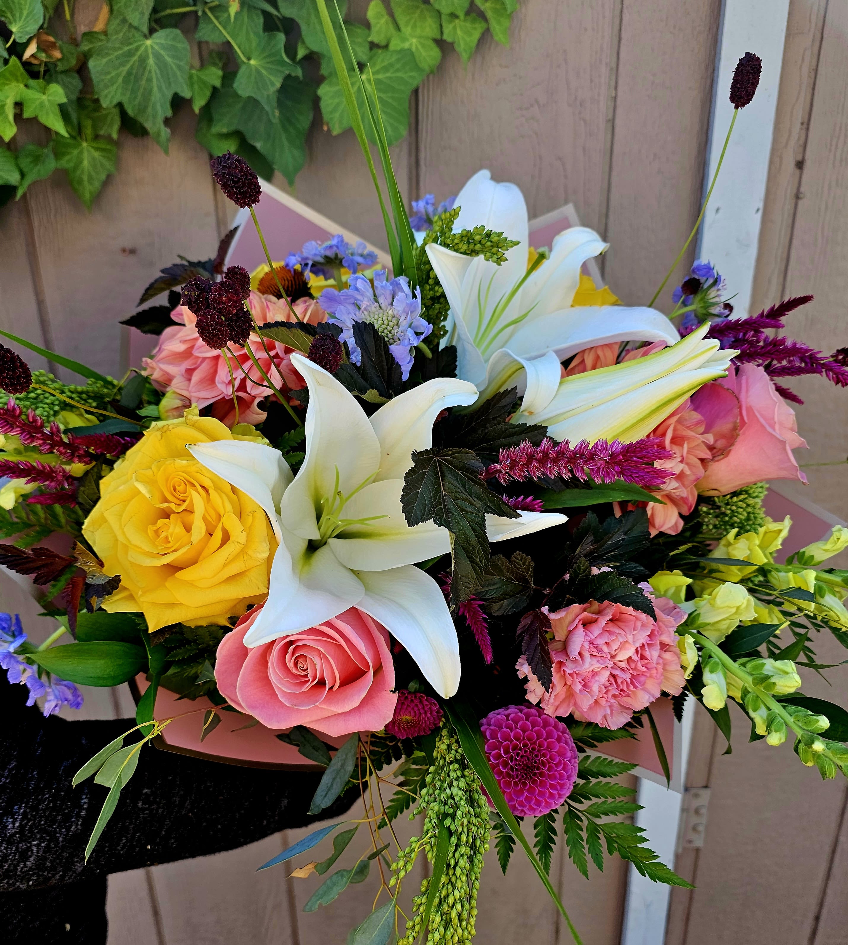 Mixed bouquet with white lilies, pink and yellow roses, and bright accent flowers