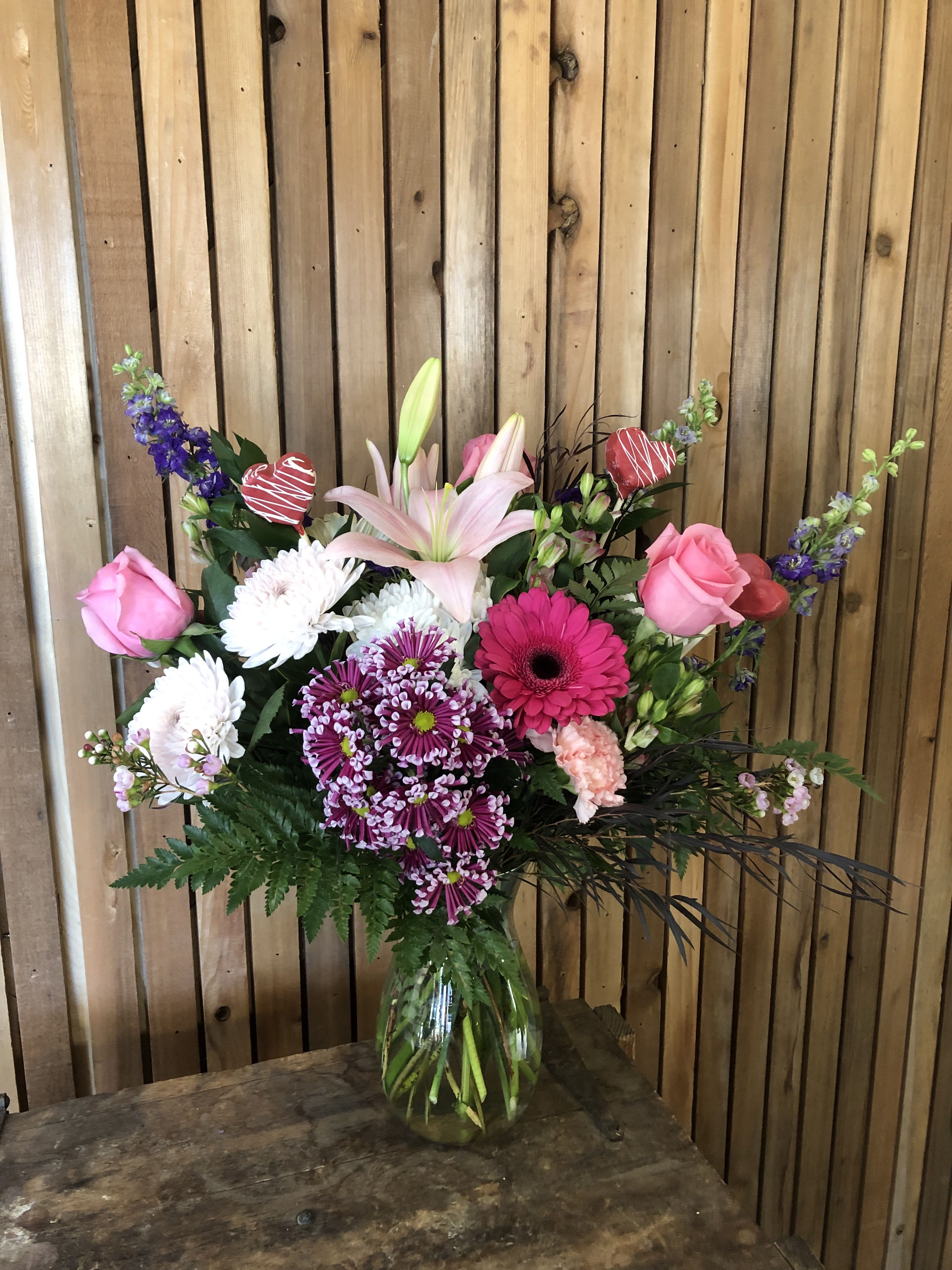 Mixed bouquet in a glass vase with pink roses, lilies, and purple blooms