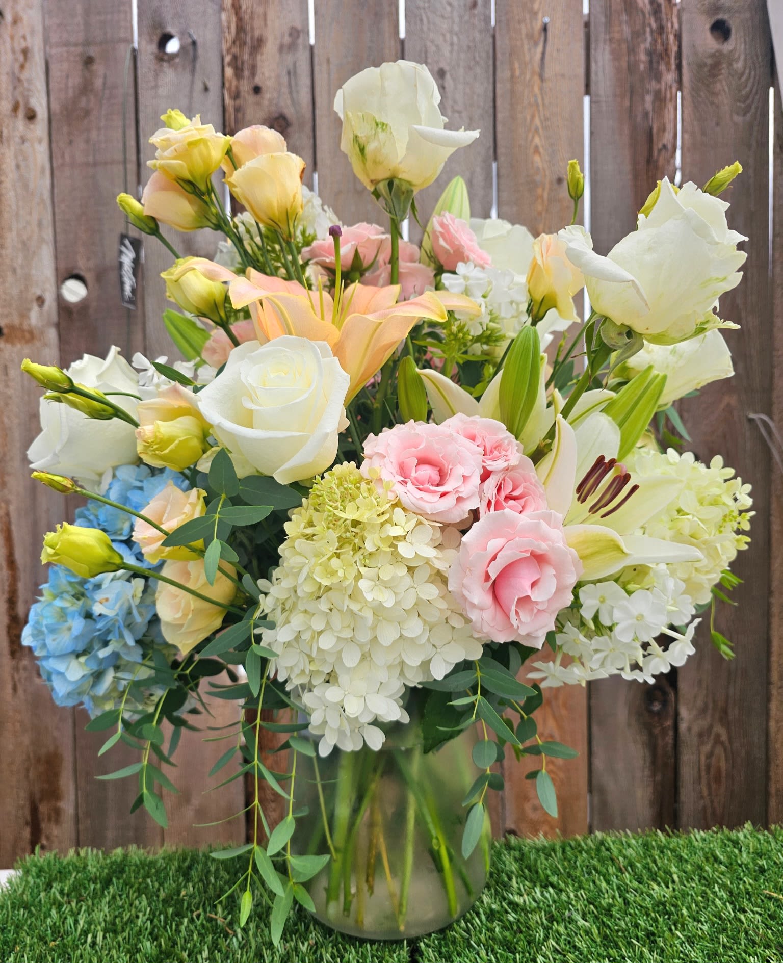 Pastel mixed bouquet in a glass vase with roses, lilies, hydrangeas, and lisianthus