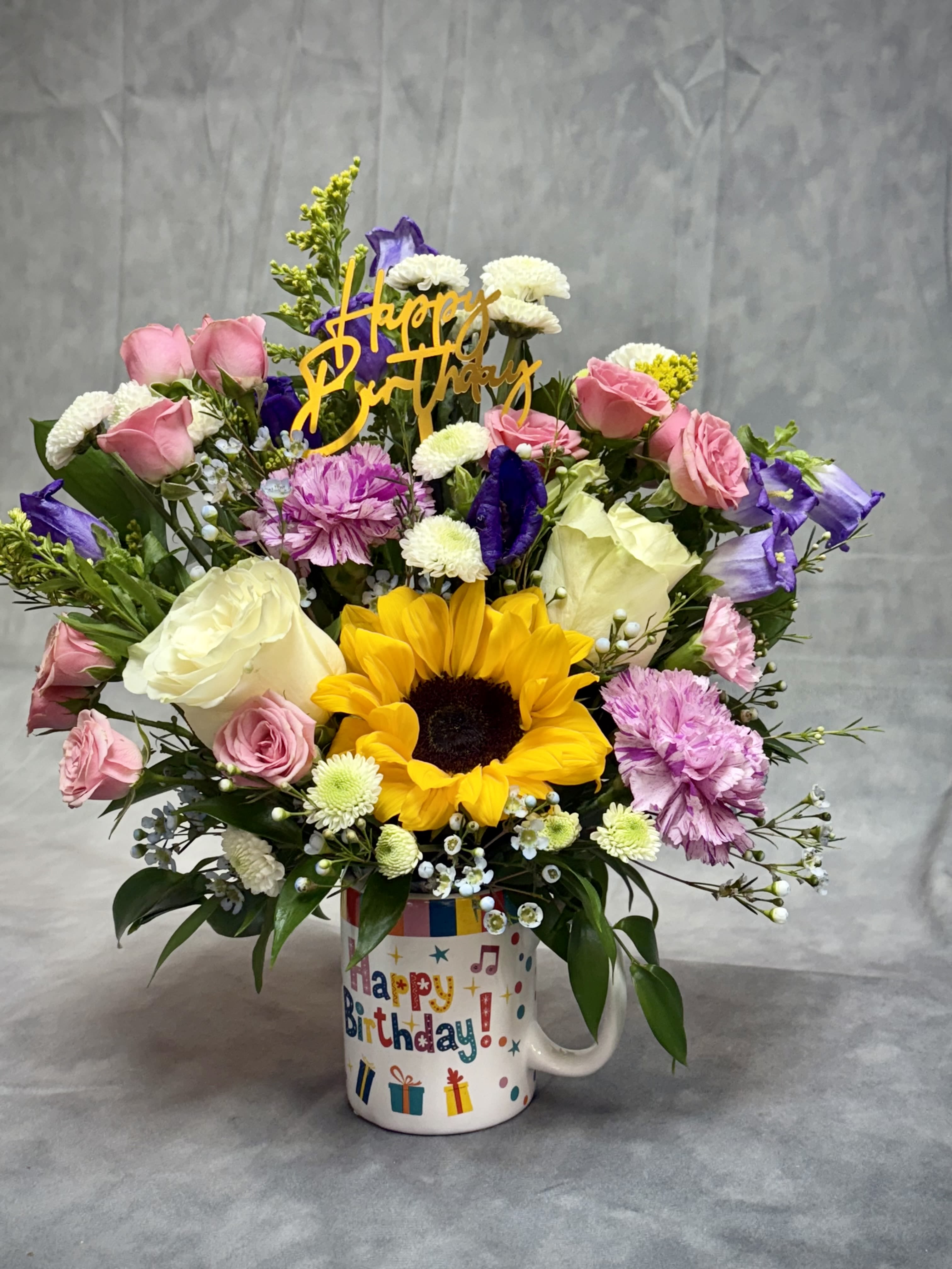 Birthday bouquet in a mug with sunflowers, roses, and mixed blooms