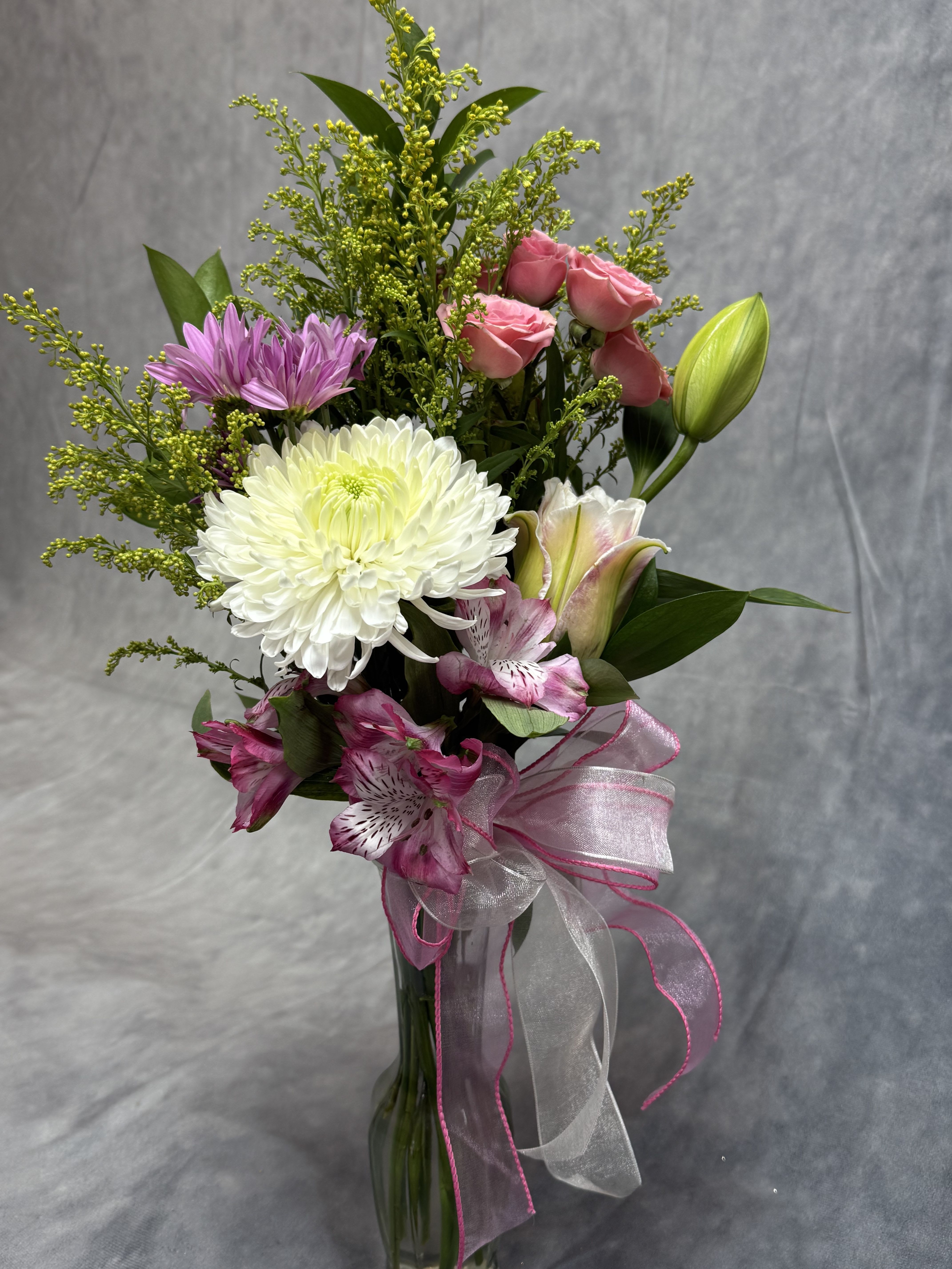Bouquet of pink roses, white chrysanthemum, and lilies in a glass vase