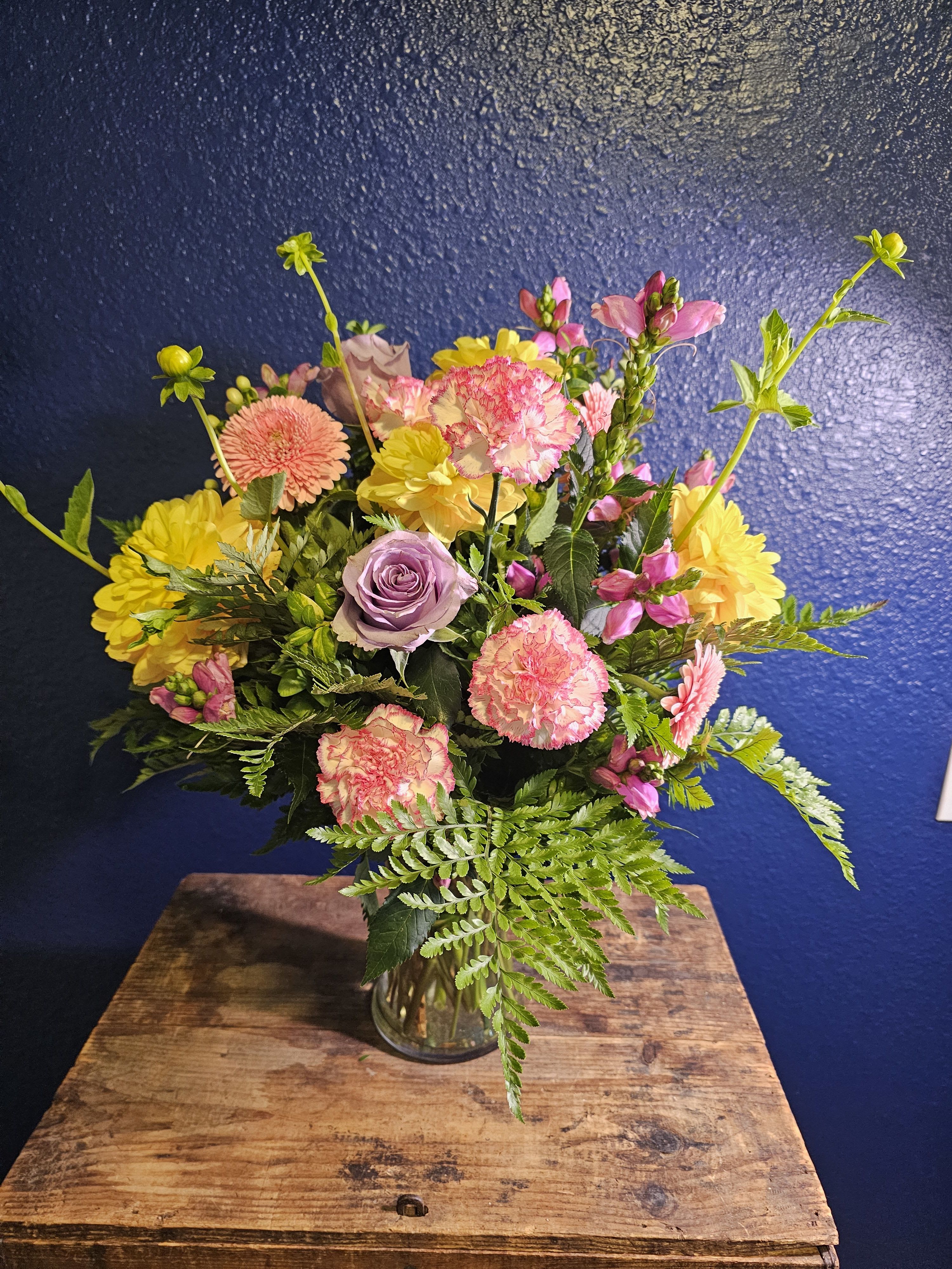 Mixed bouquet in a clear glass vase with pink, yellow, and lavender blooms