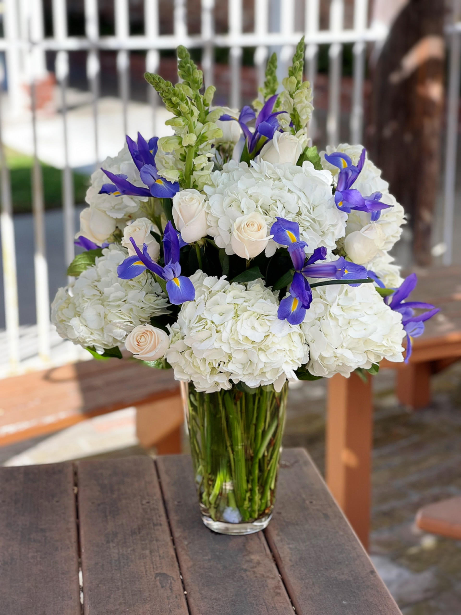White hydrangea and roses with purple irises in a glass vase