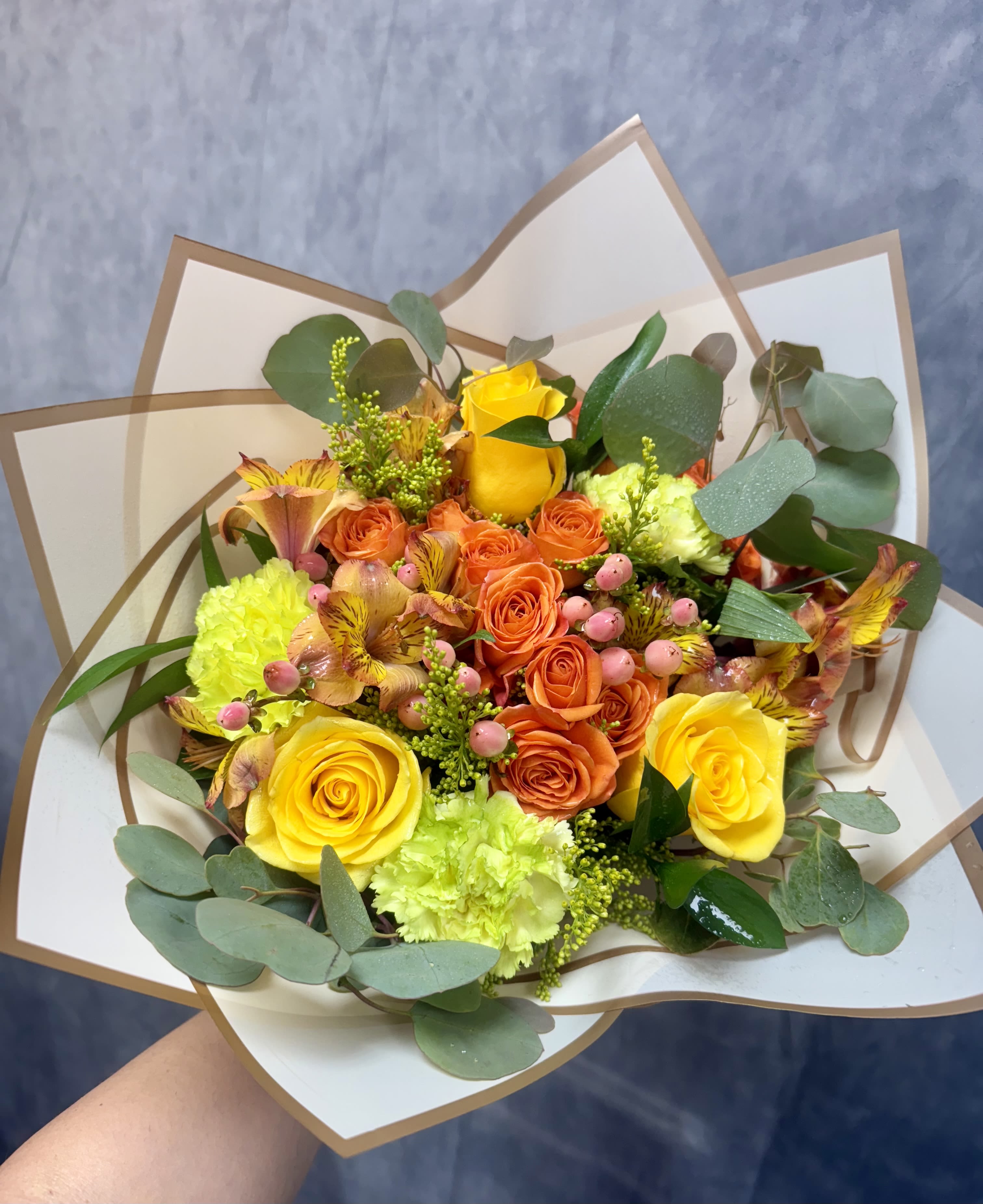 Bouquet of yellow and orange roses with green and pink accents