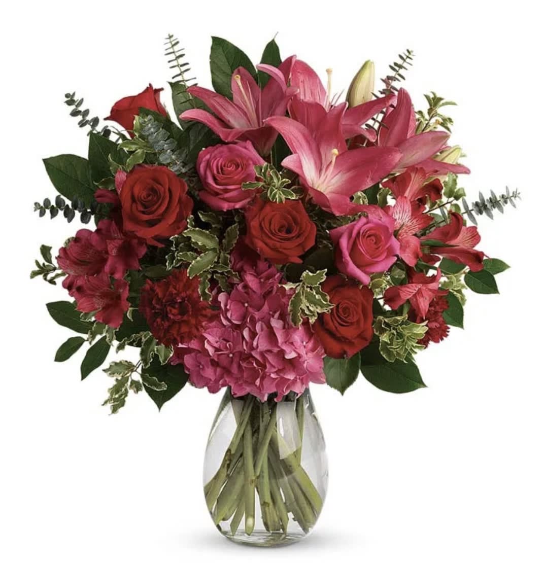 Bouquet of pink lilies and red roses in a clear glass vase