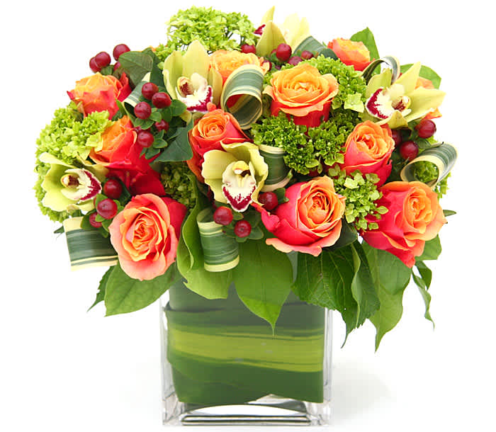 Orange roses and pale green orchids in a clear square vase